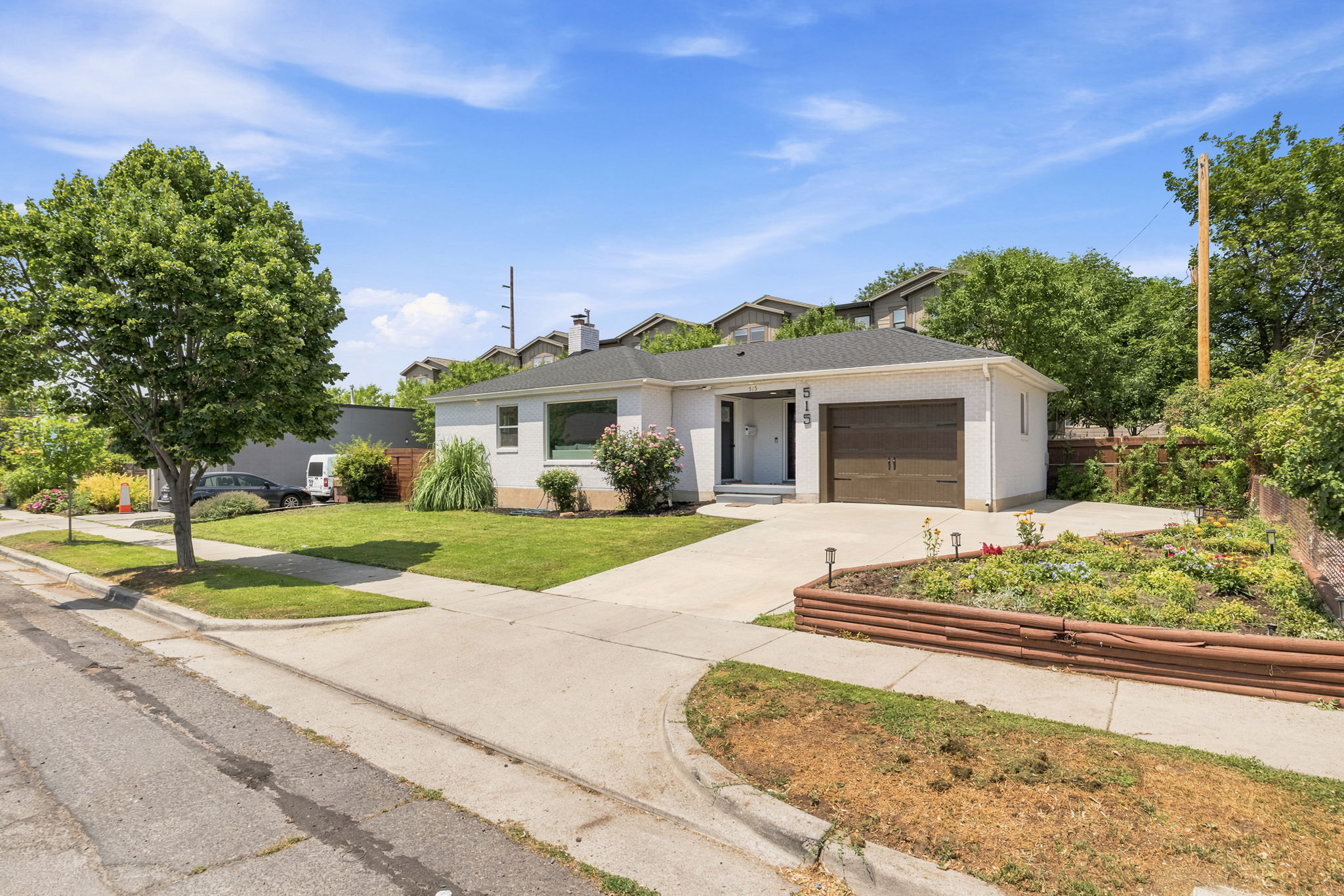 White exterior residence featuring a dark asphalt shingle roof, attached single-car garage with a wood-finish door, and a paved driveway