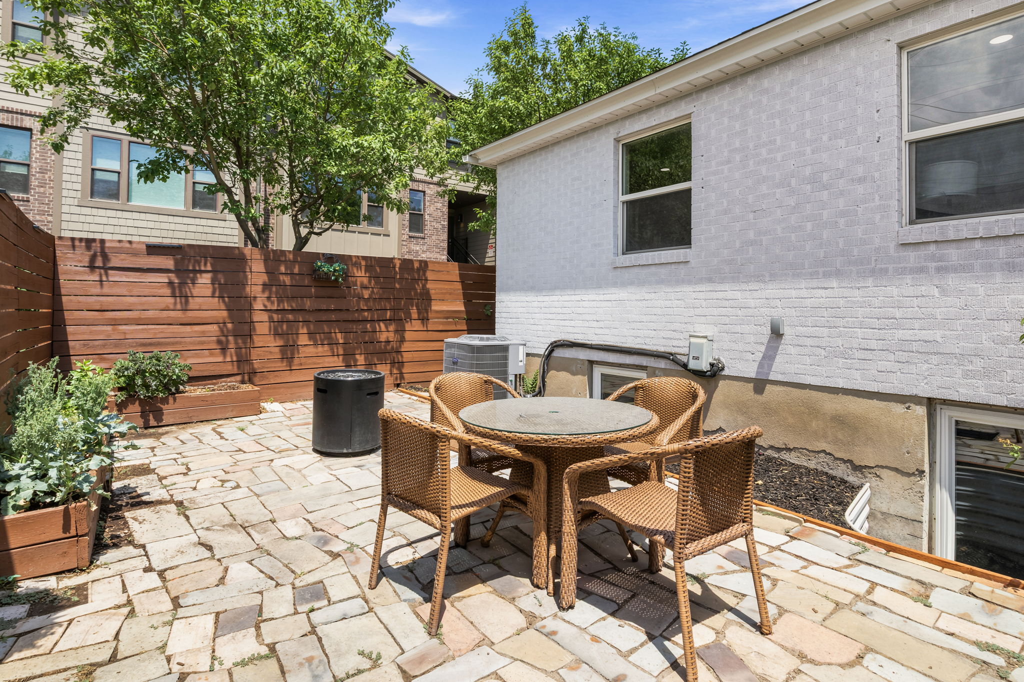 Private outdoor patio featuring a patterned stone paver surface and wood privacy fencing