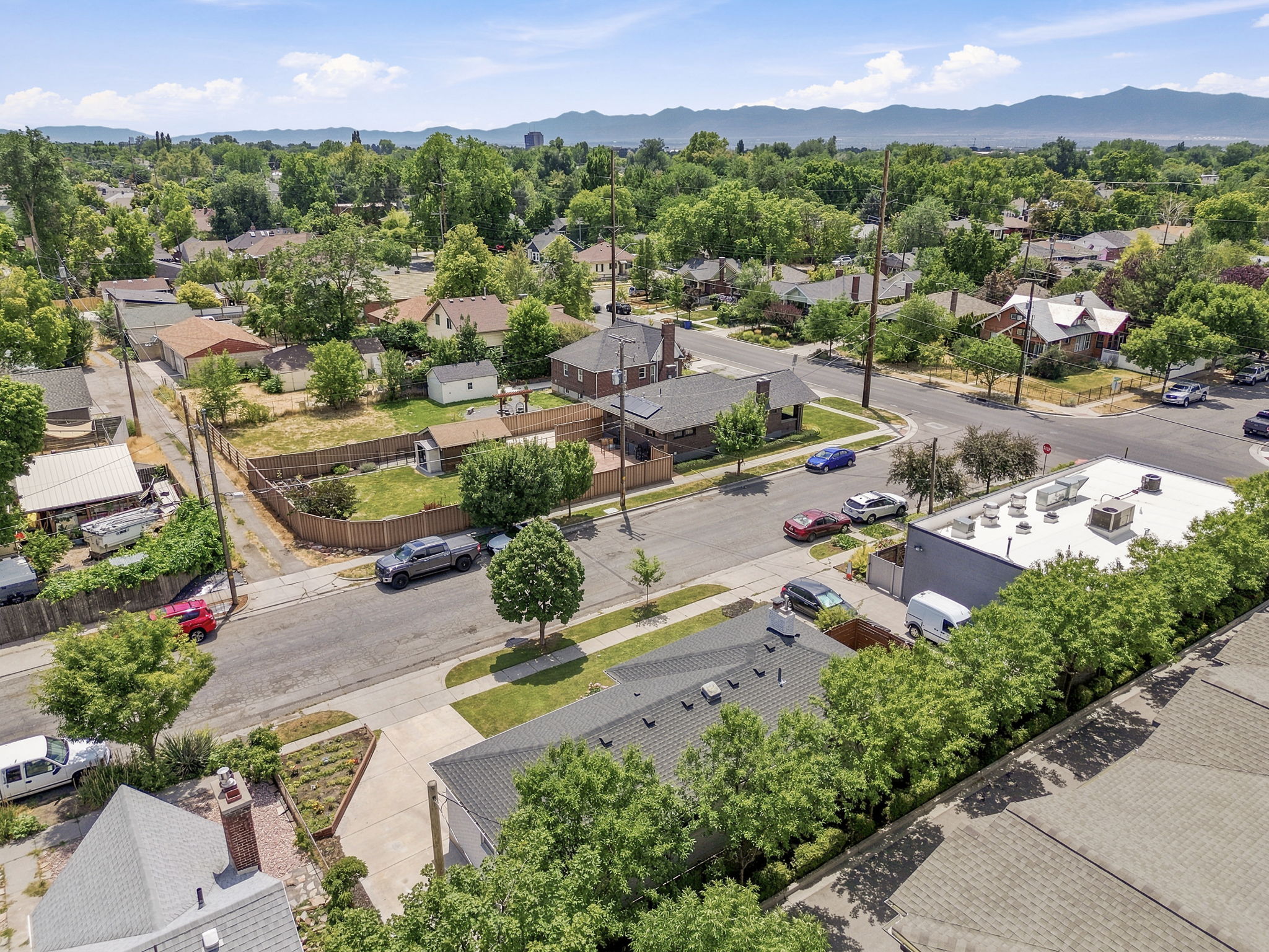 Established neighborhood with mature trees, mountain backdrop, residential street, and visible rooftops