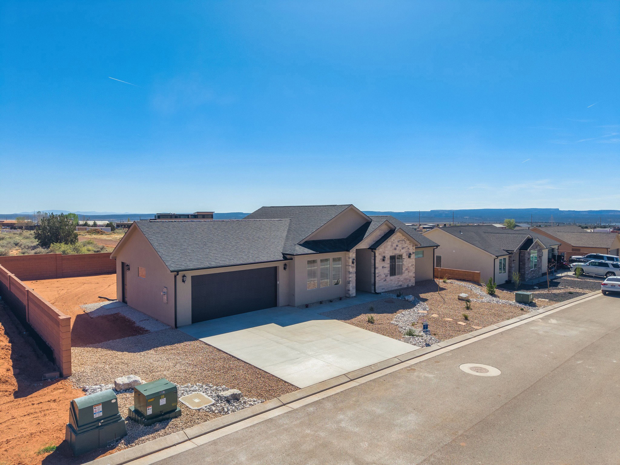 Contemporary stucco exterior with stone accents and a dark shingle roof
