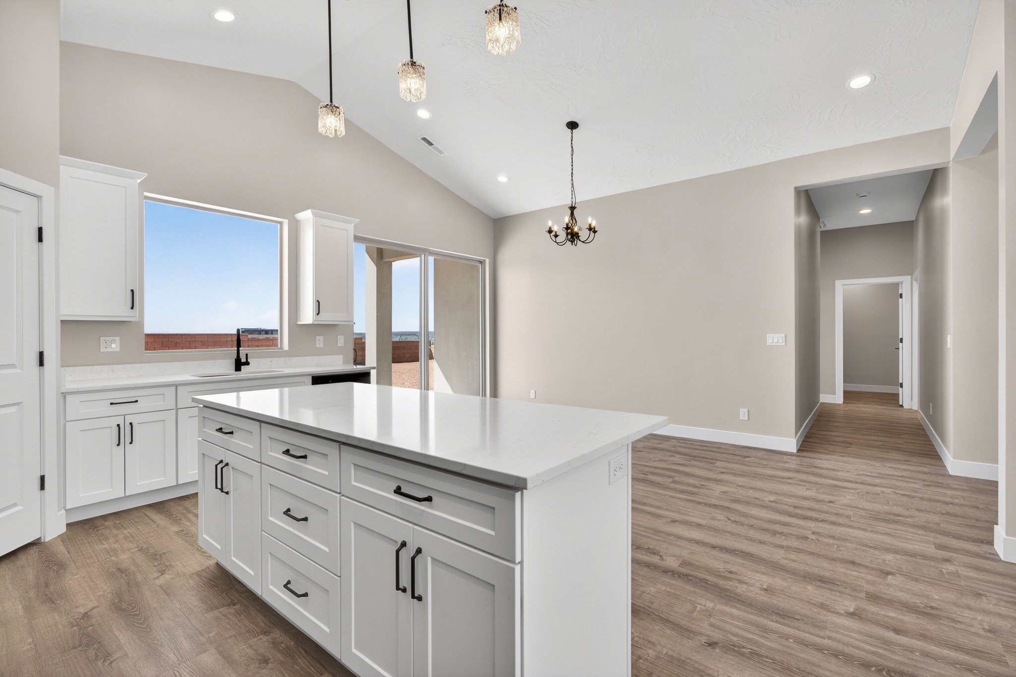 Open-concept kitchen and dining area featuring a vaulted ceiling and wood-finish flooring