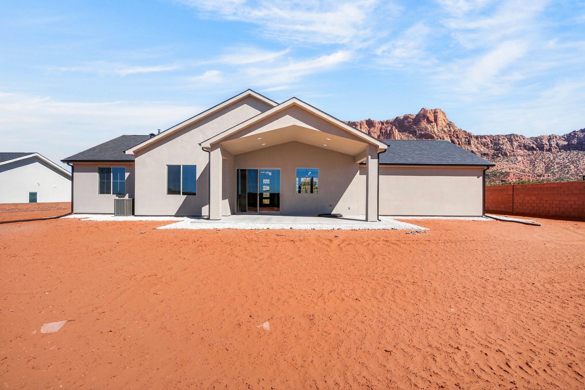 Rear exterior featuring a covered patio, sliding glass door, and a red rock mountain backdrop