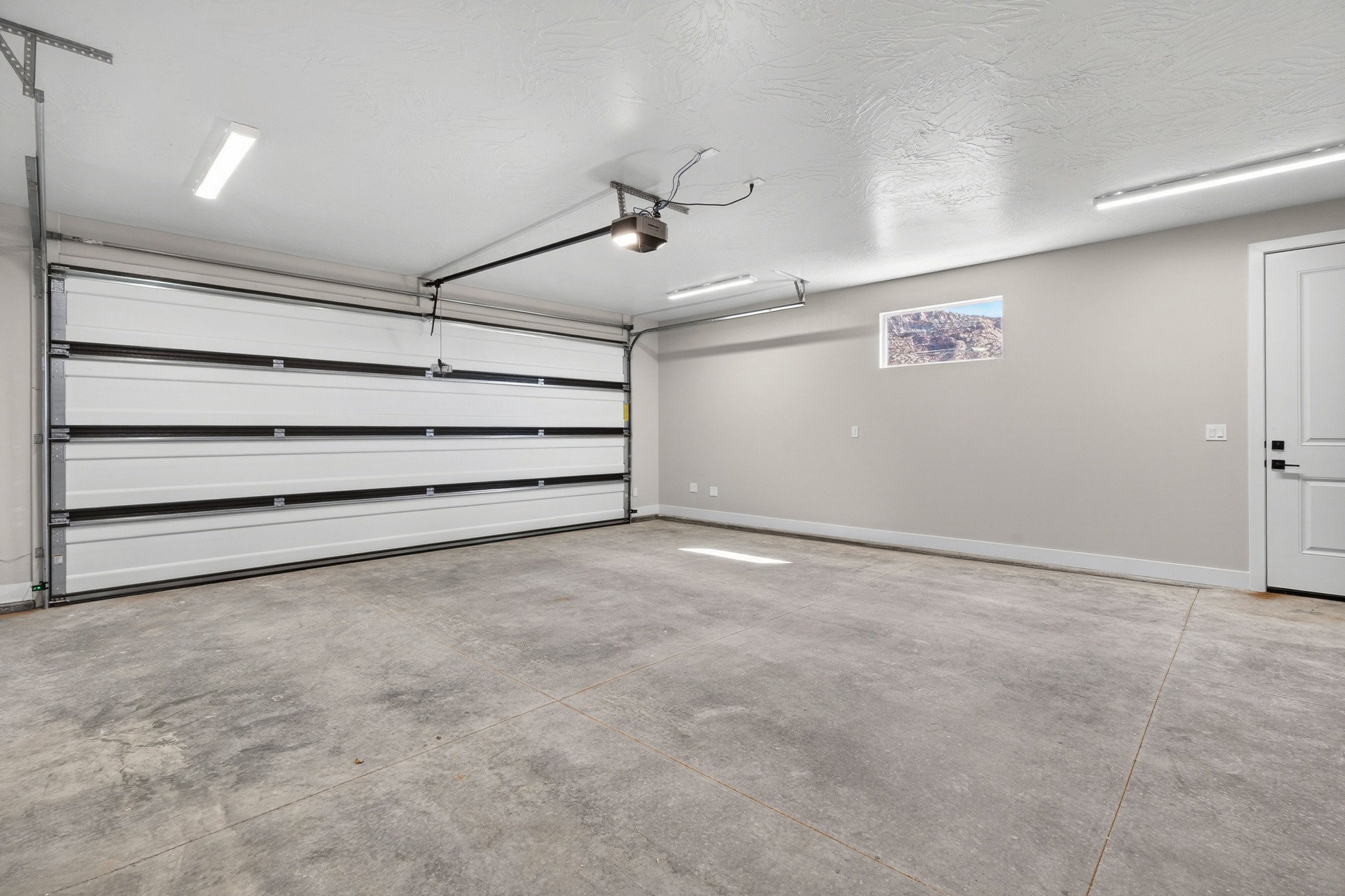Spacious garage with a concrete floor, white sectional overhead door, and a single window