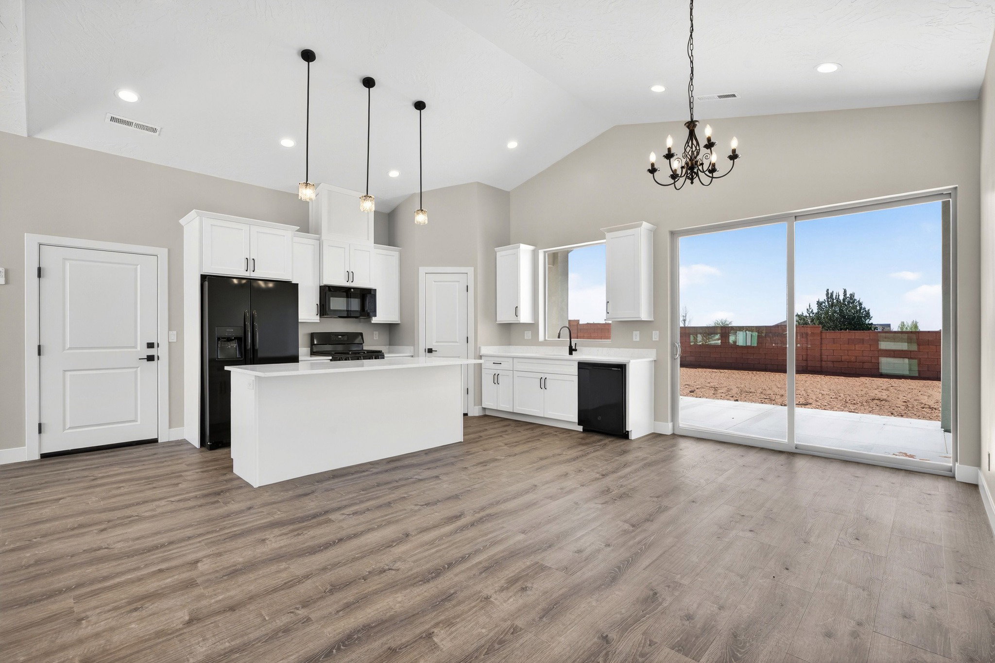 Vaulted ceiling kitchen featuring white cabinetry, a central island, and wood-finish flooring