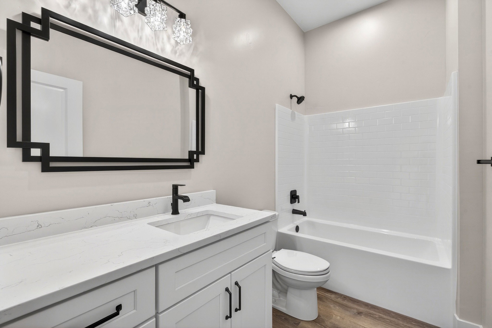 Bathroom featuring a white vanity with a light-toned countertop, black fixtures, and a decorative mirror