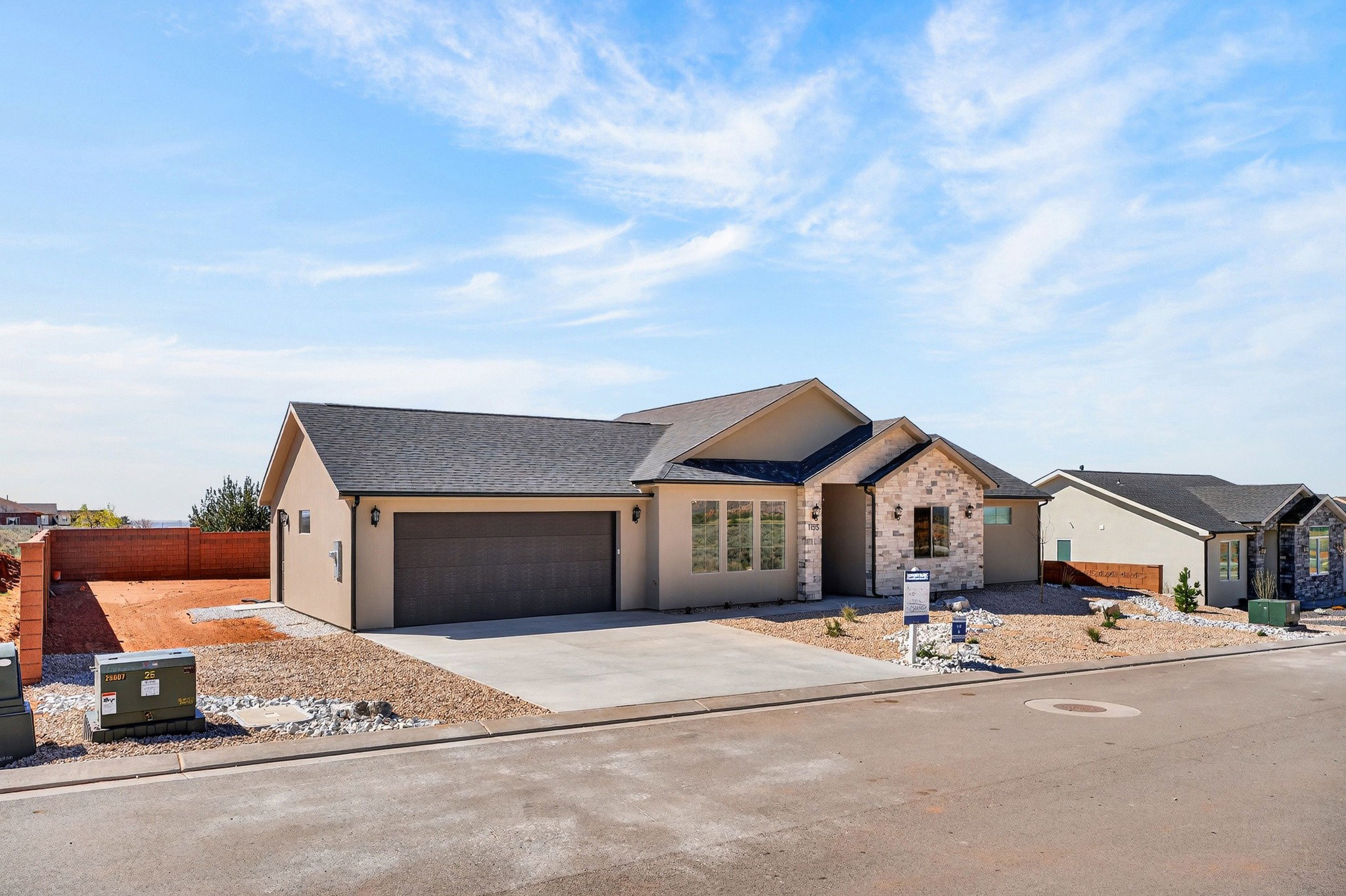 Contemporary stucco exterior with a stone accent facade, featuring a dark shingle roof and an integrated two-car garage