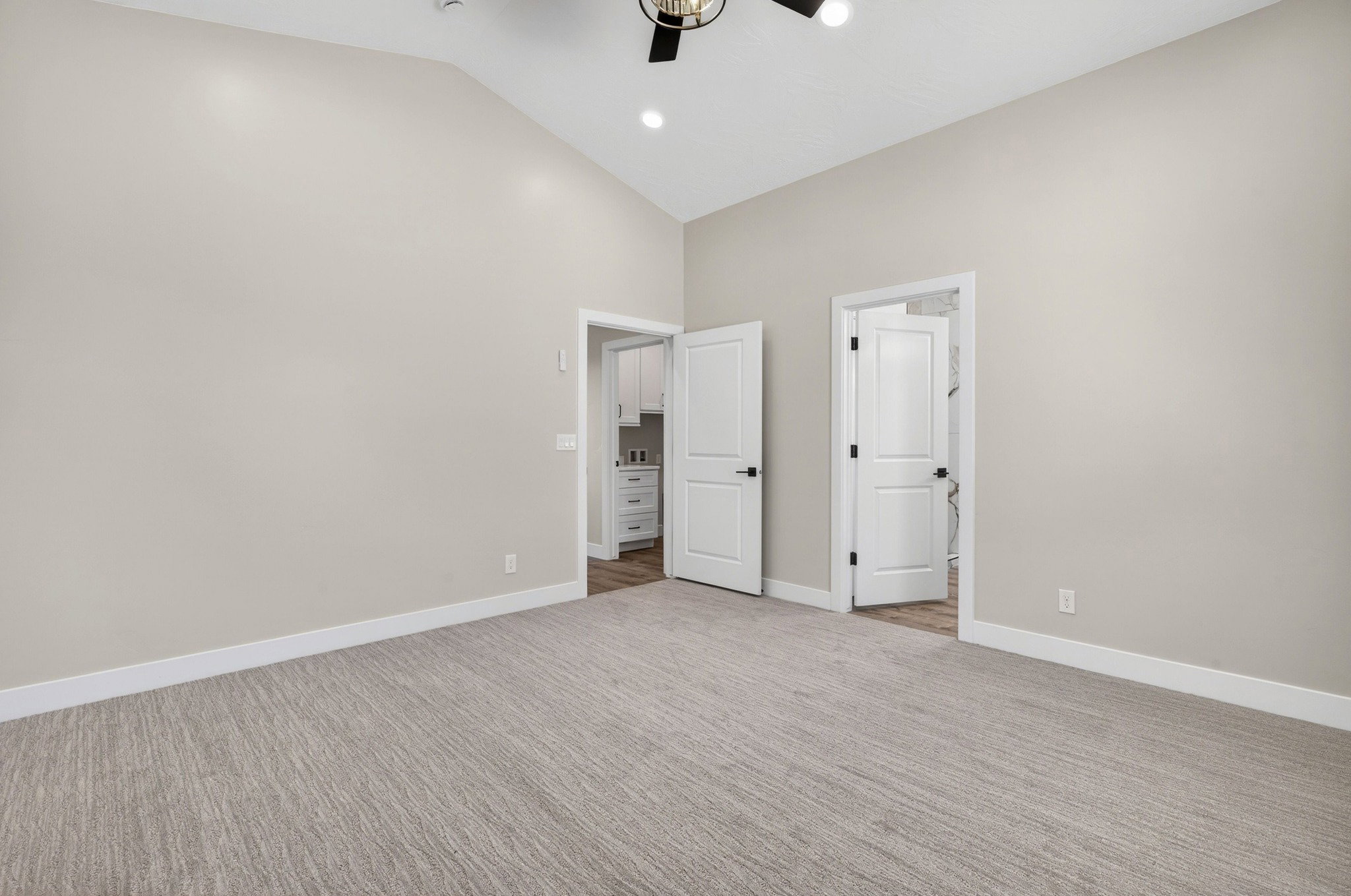 Spacious room featuring vaulted ceilings, light-colored walls, and patterned carpeting