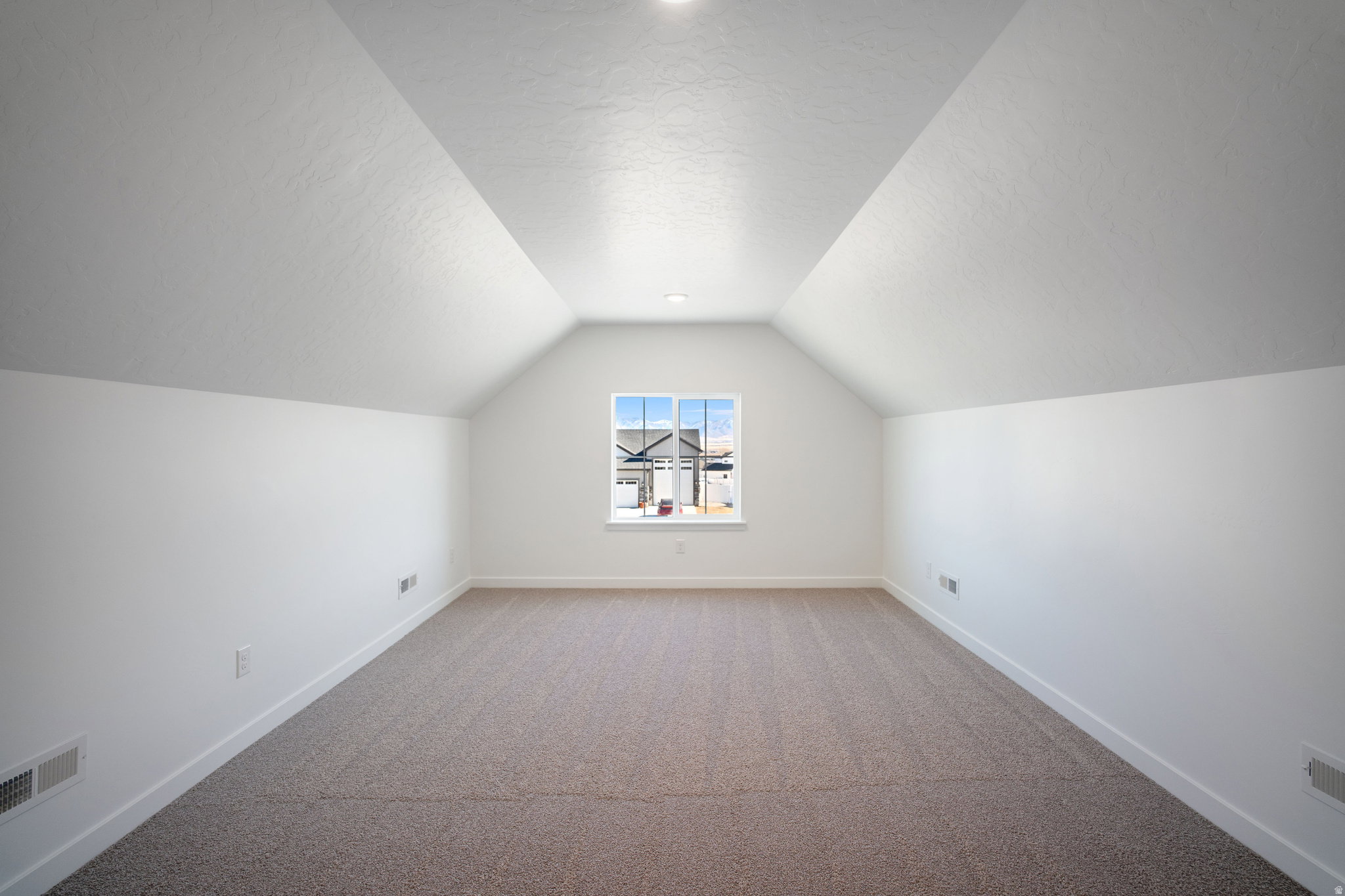Spacious room featuring vaulted ceilings, a central window, recessed lighting, white walls, and neutral carpeting
