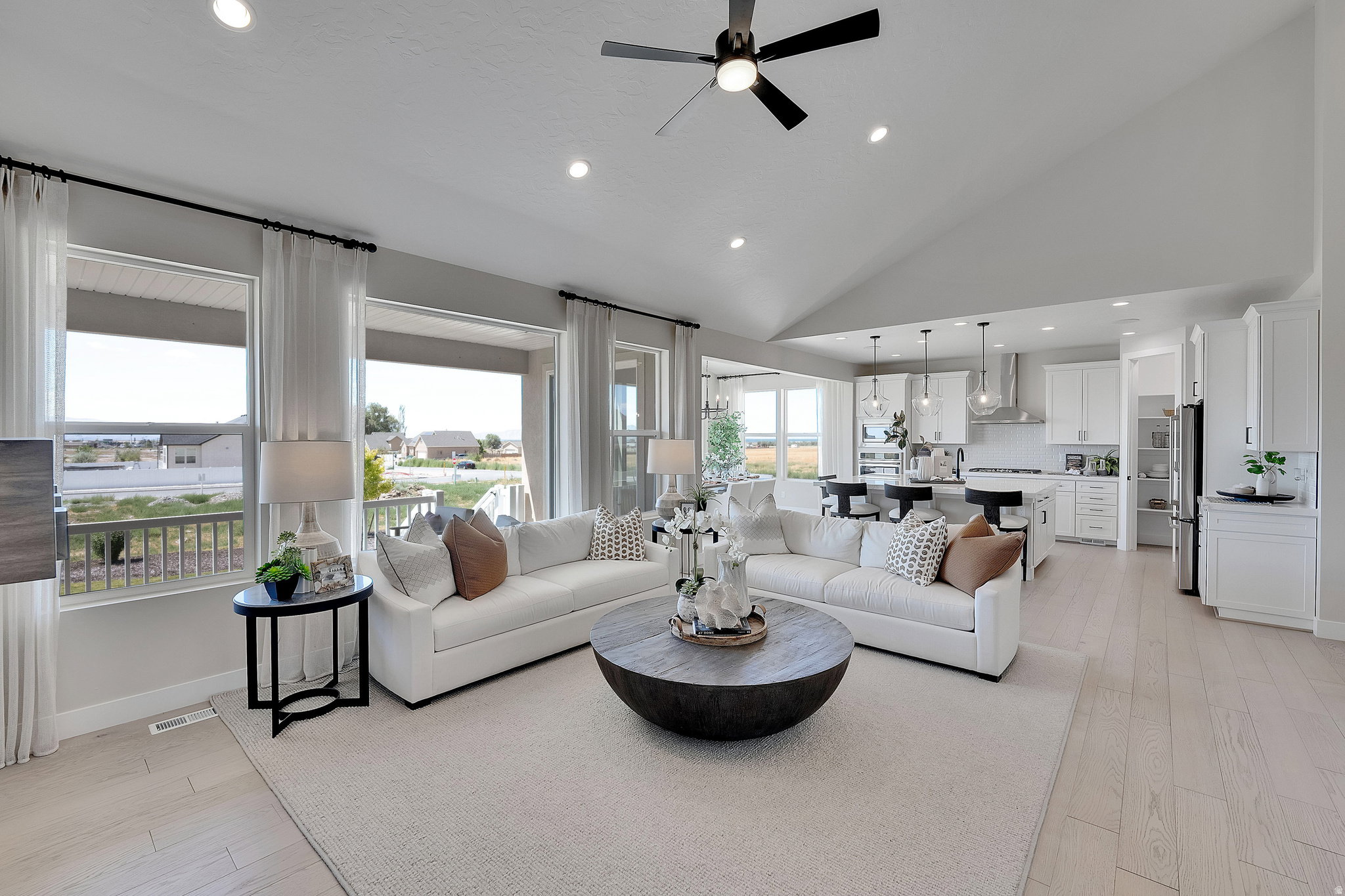 Vaulted ceilings highlight this expansive open-concept living space with recessed lighting and a ceiling fan