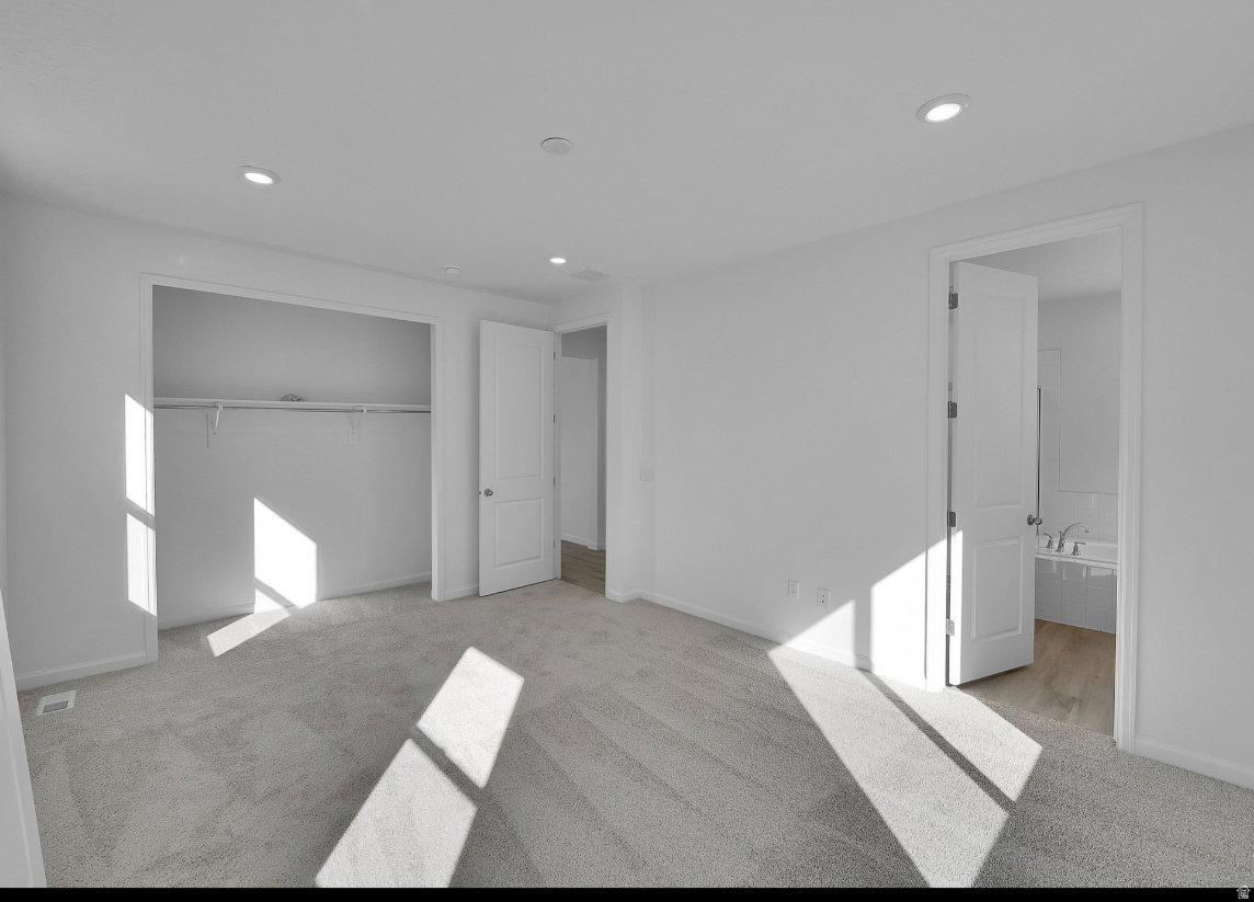 Spacious room featuring light gray carpet, recessed lighting, and a white interior color palette