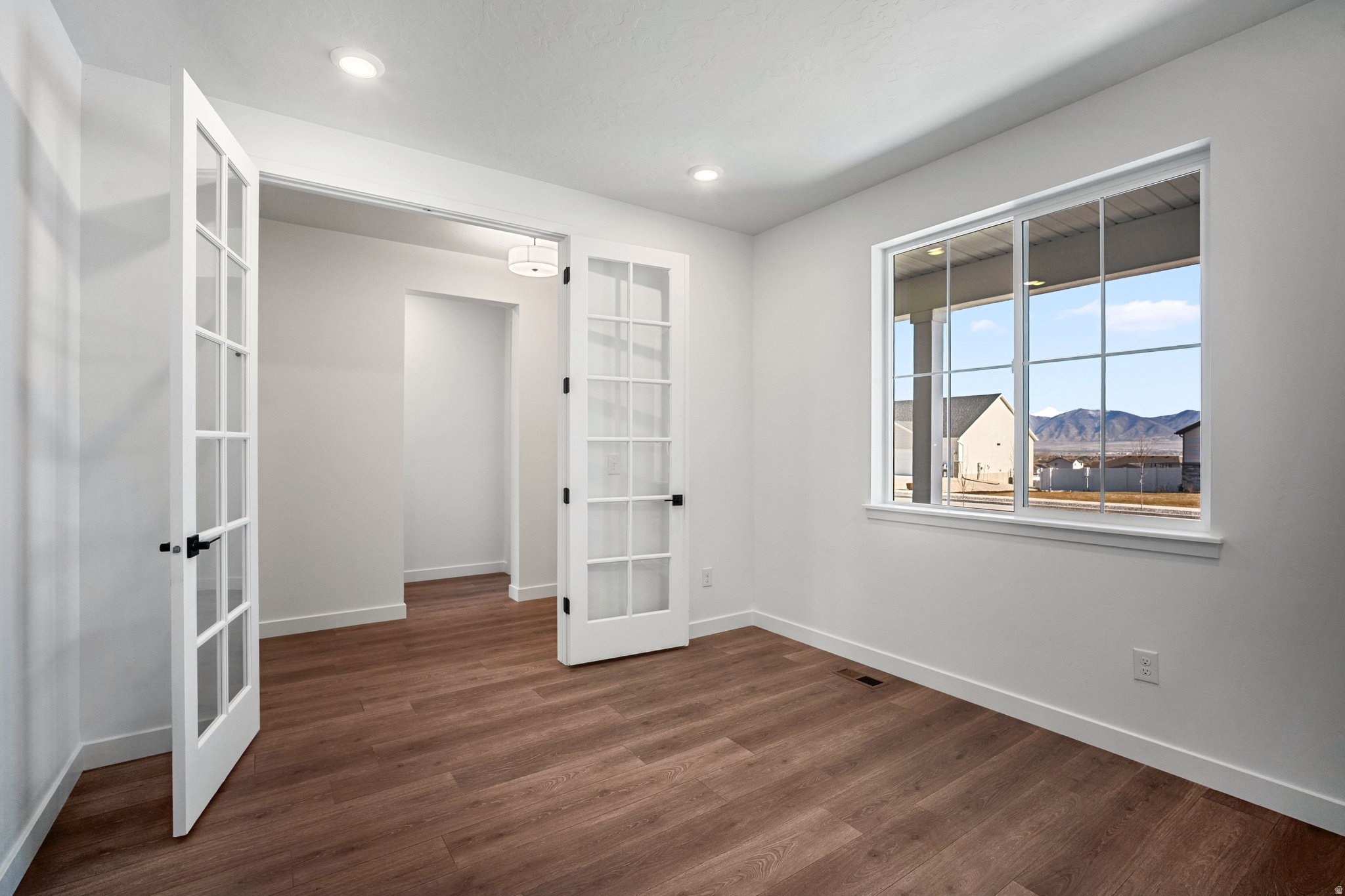 Room featuring wood-finish flooring, recessed lighting, and a large window with mountain scenery