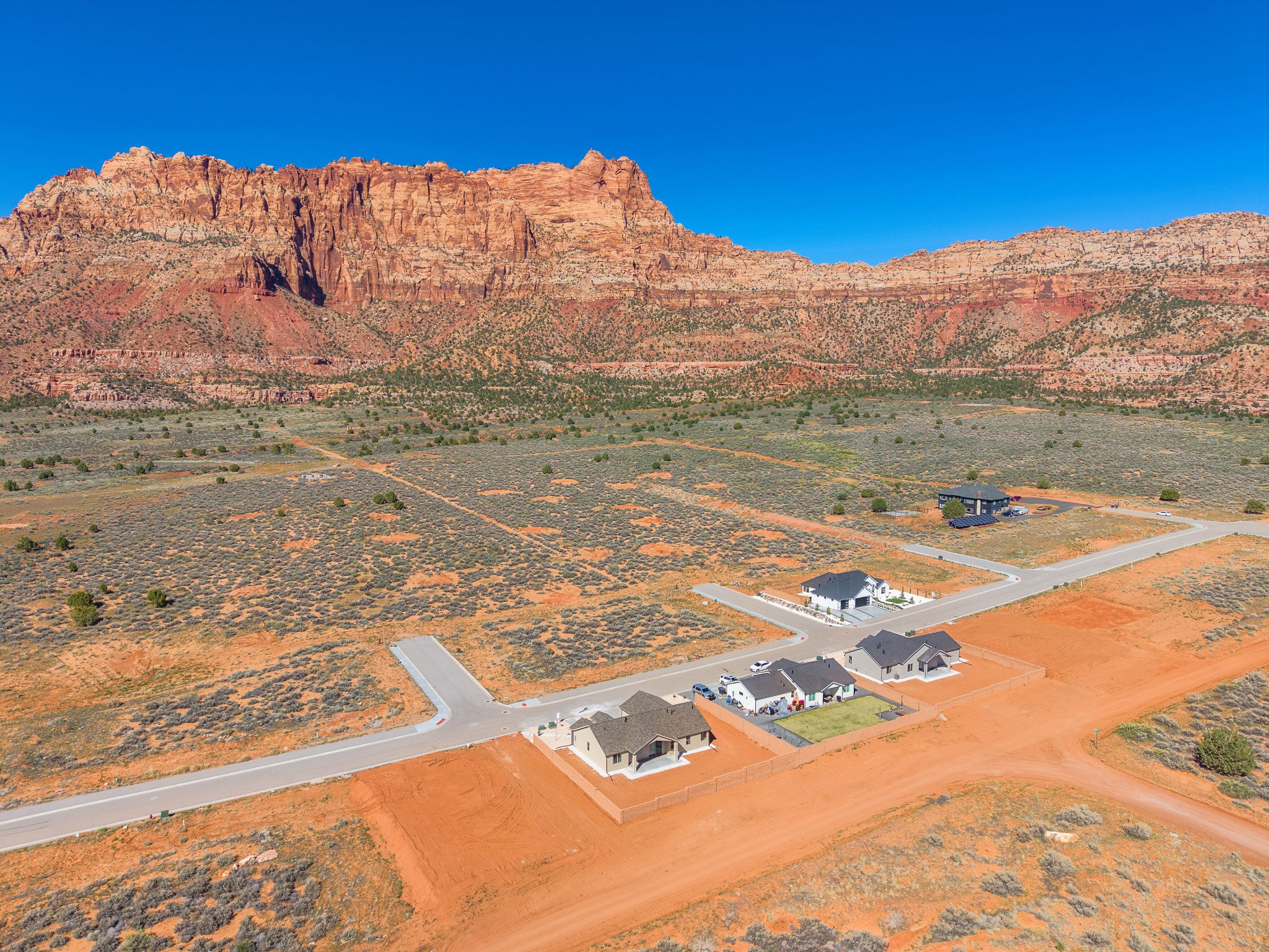 Expansive desert landscape featuring red rock mountains and new residential construction