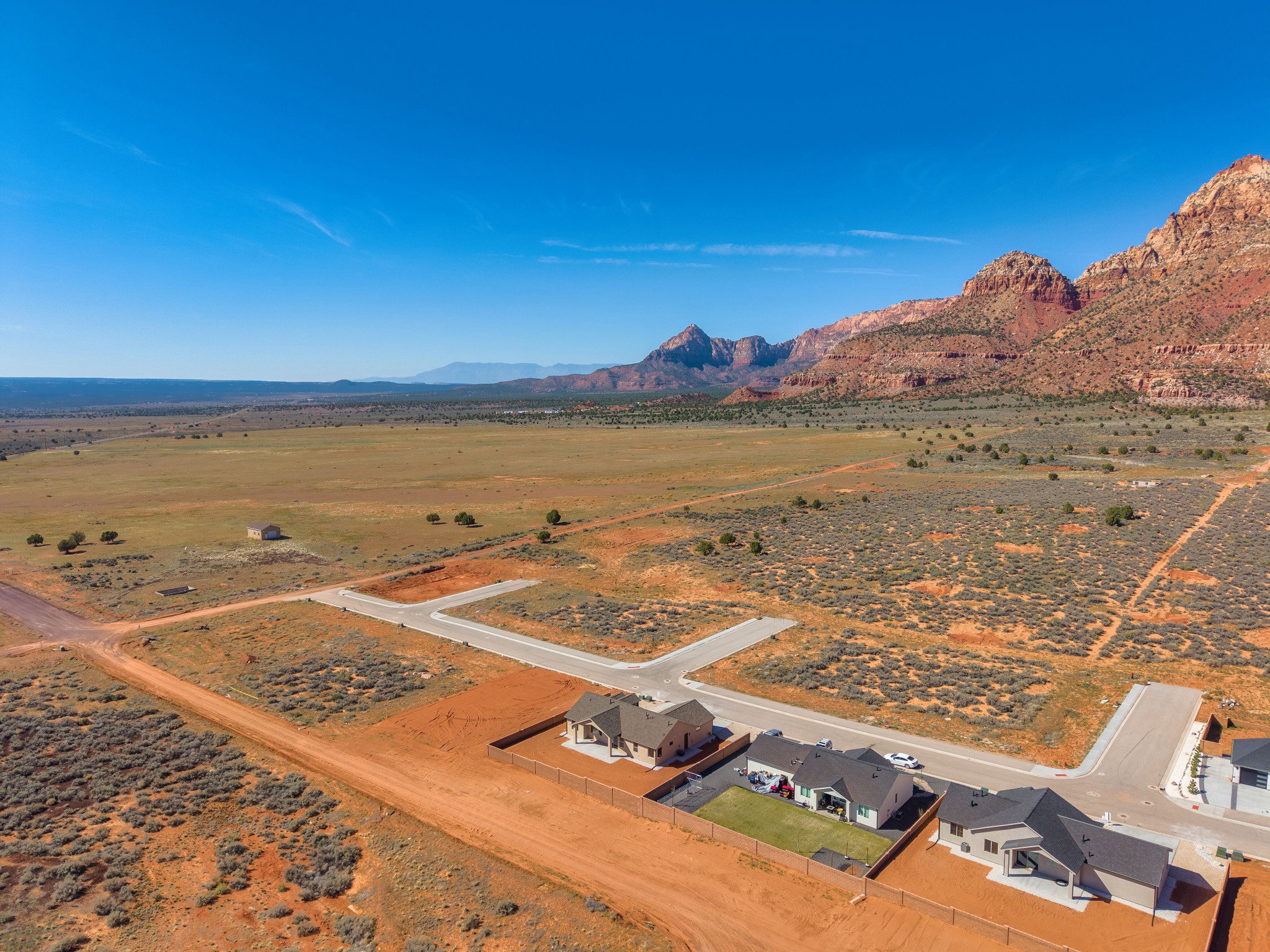Expansive desert landscape featuring red rock mountains and a distant flat plain