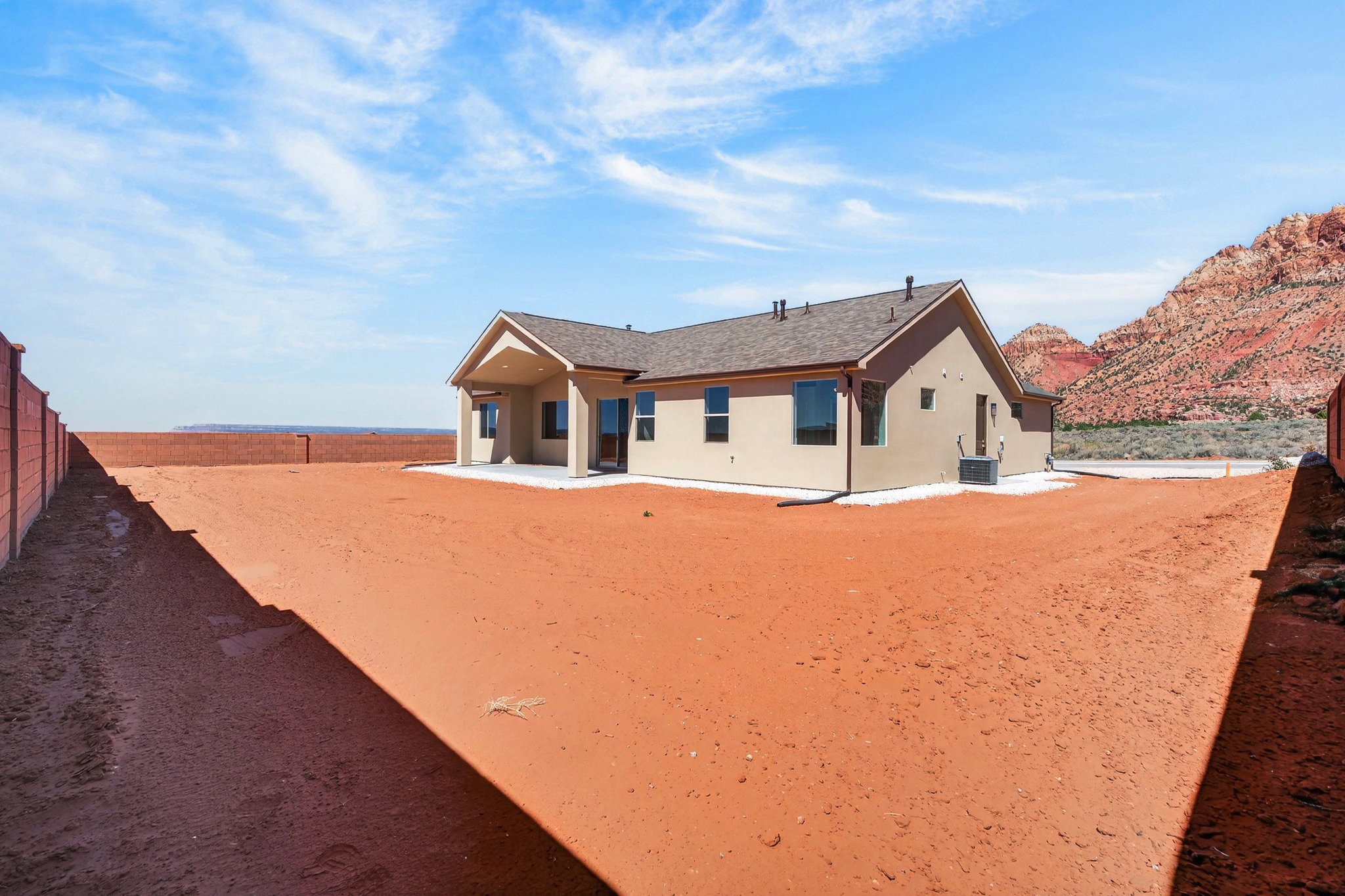 Newly constructed residence featuring stucco siding, a covered patio, and a shingled roof