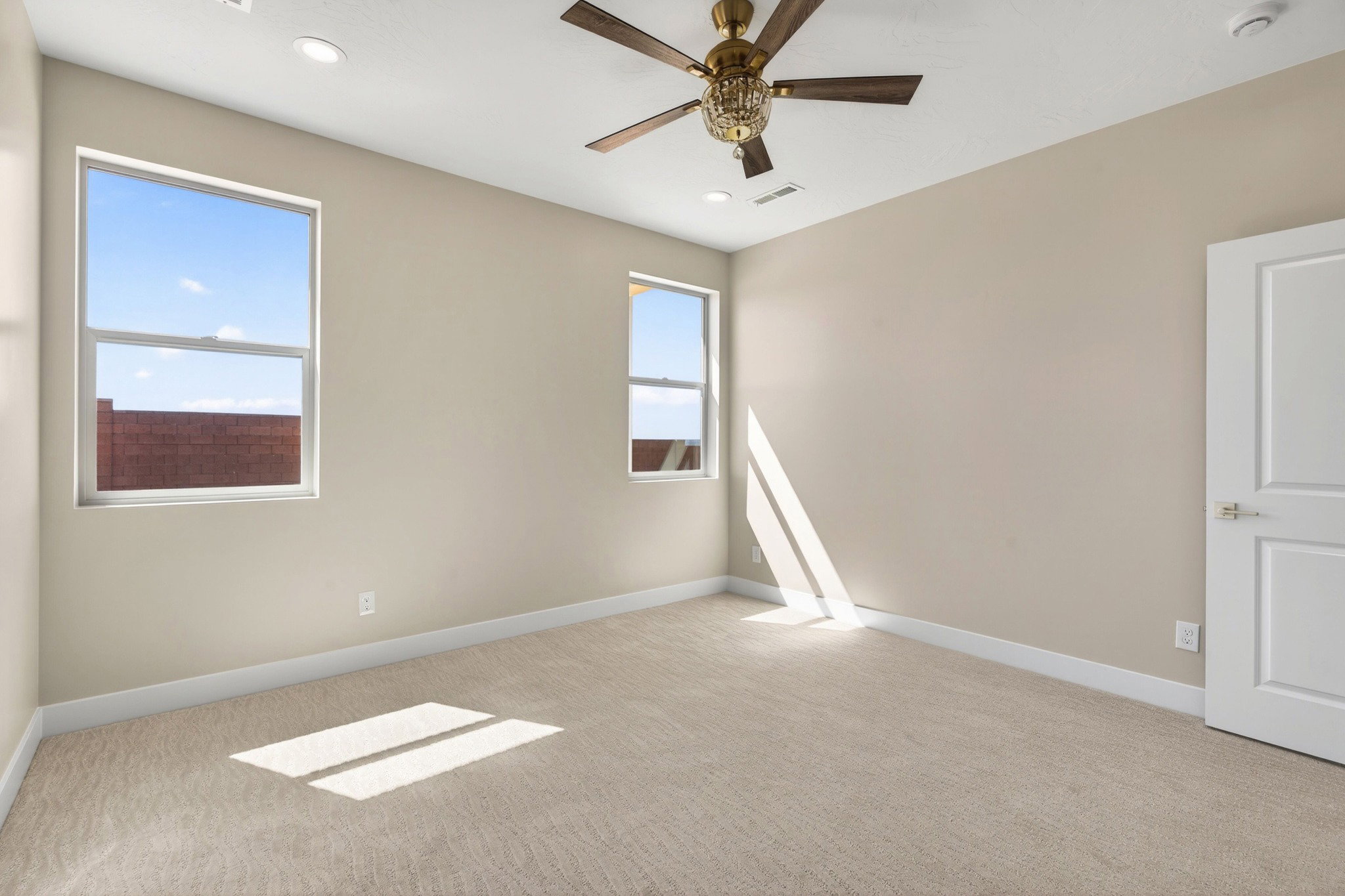 Carpeted room featuring two windows, recessed lighting, and a ceiling fan with an ornate light fixture