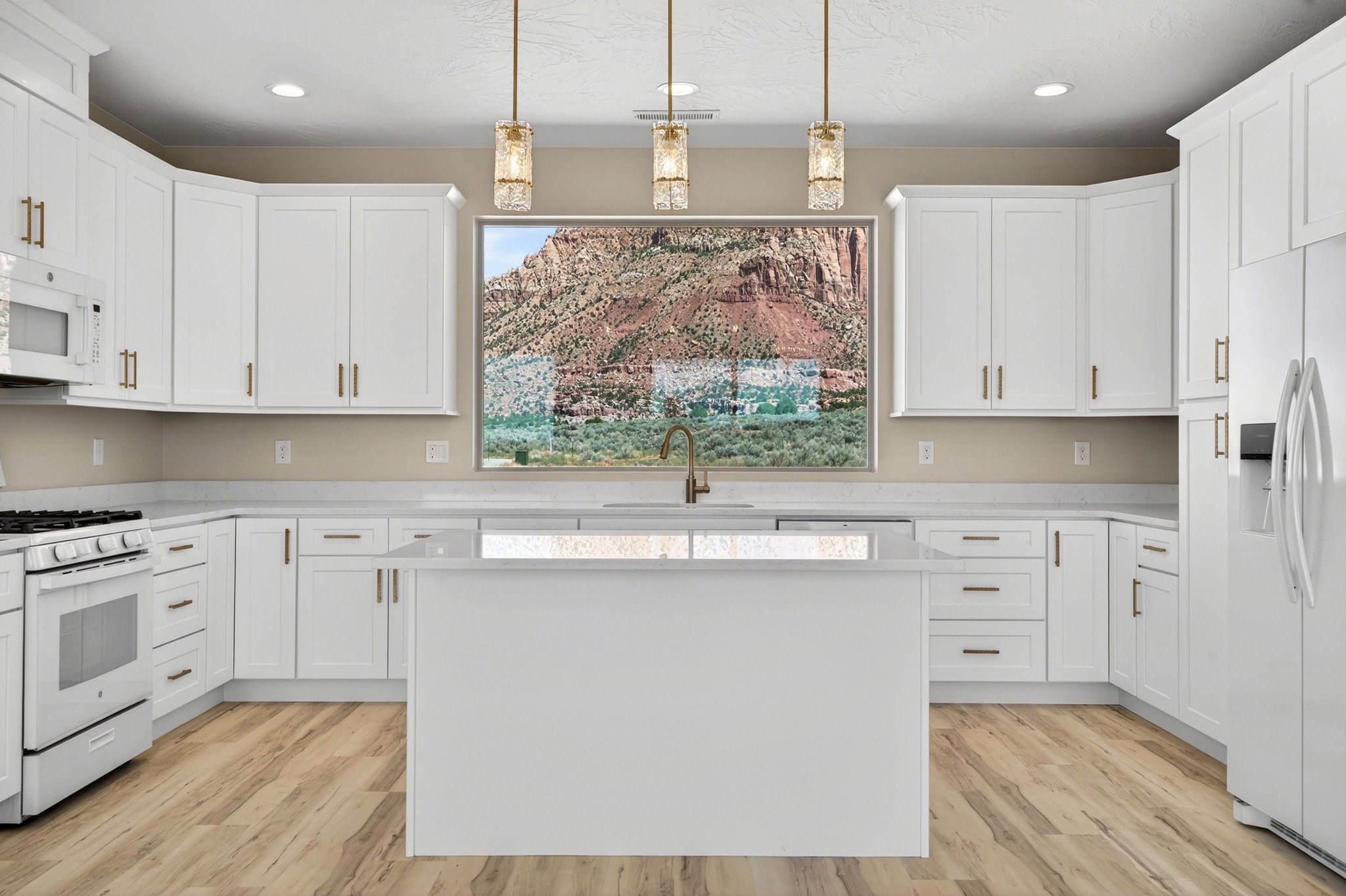 Modern kitchen featuring white cabinetry, a center island with a sink, stainless steel appliances, wood-finish flooring, and pendant lighting