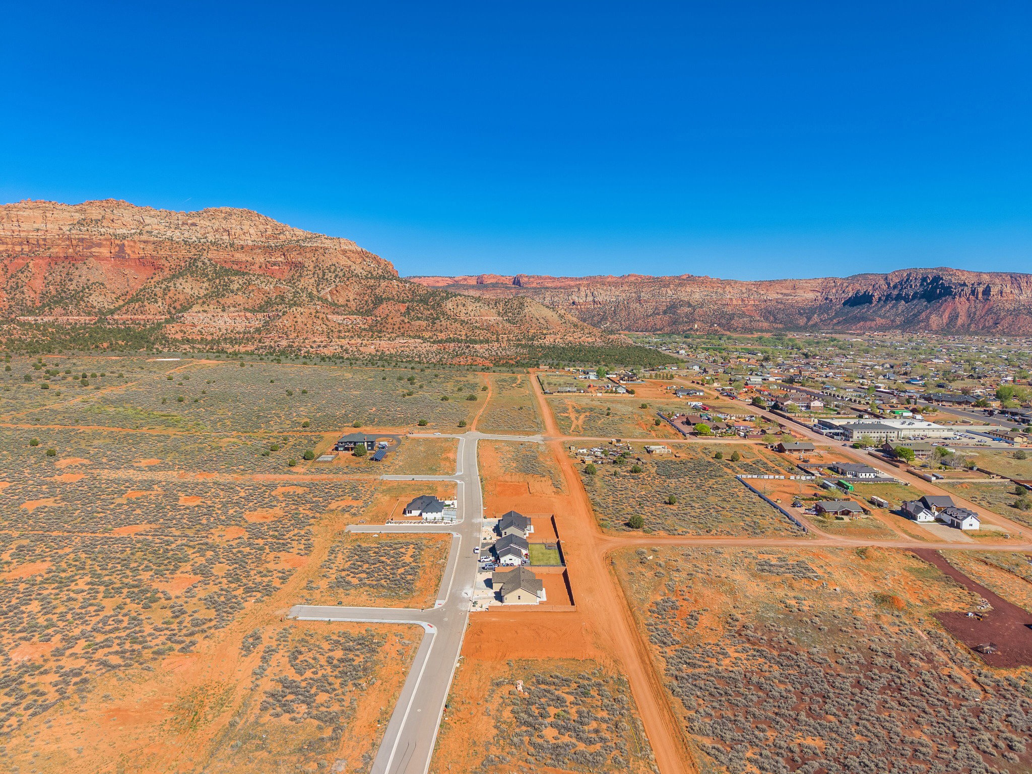 Expansive desert landscape featuring graded roads and building pads, bordered by distant mountainous terrain