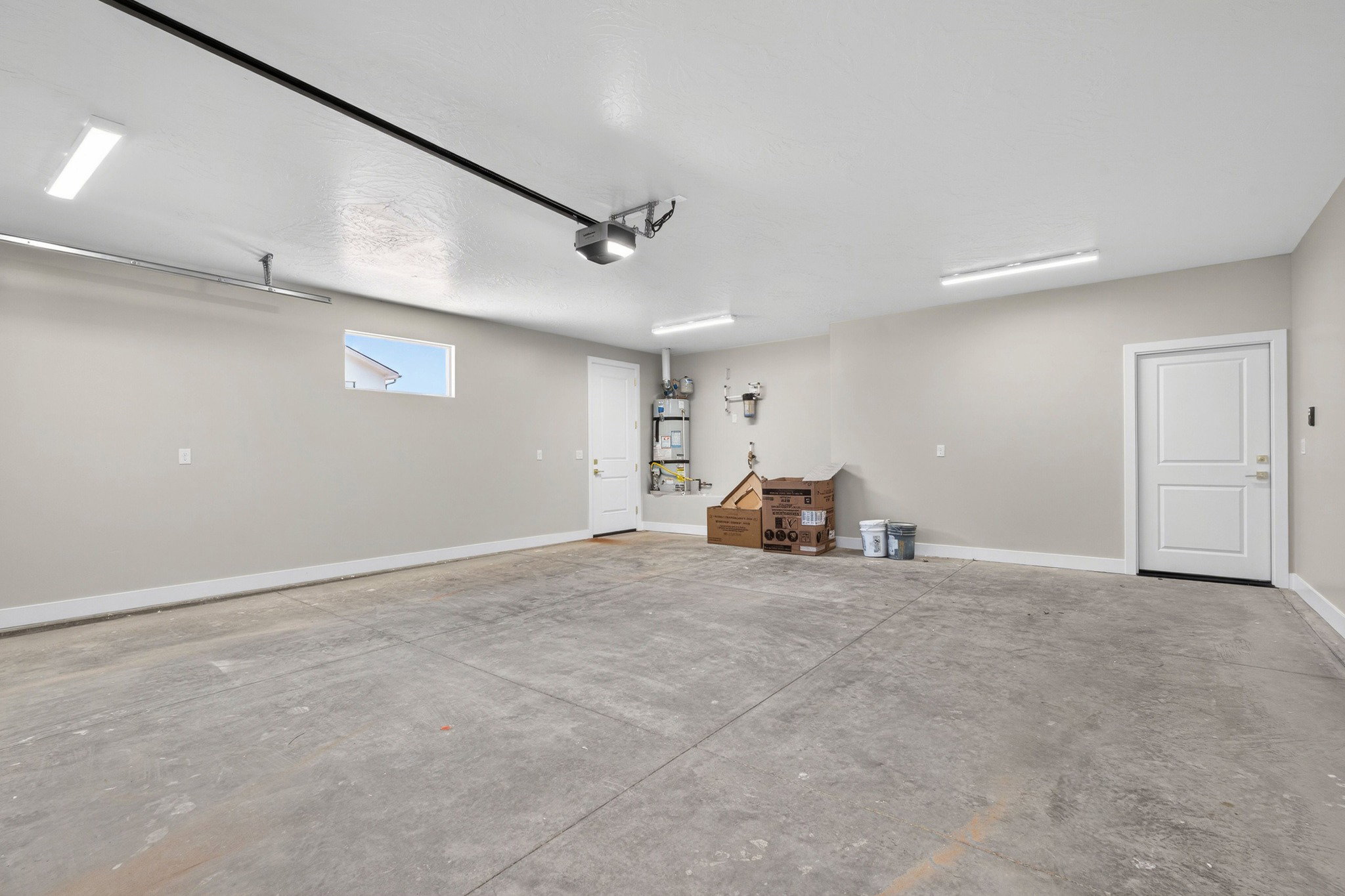 Spacious garage with concrete flooring, neutral wall tones, and overhead strip lighting