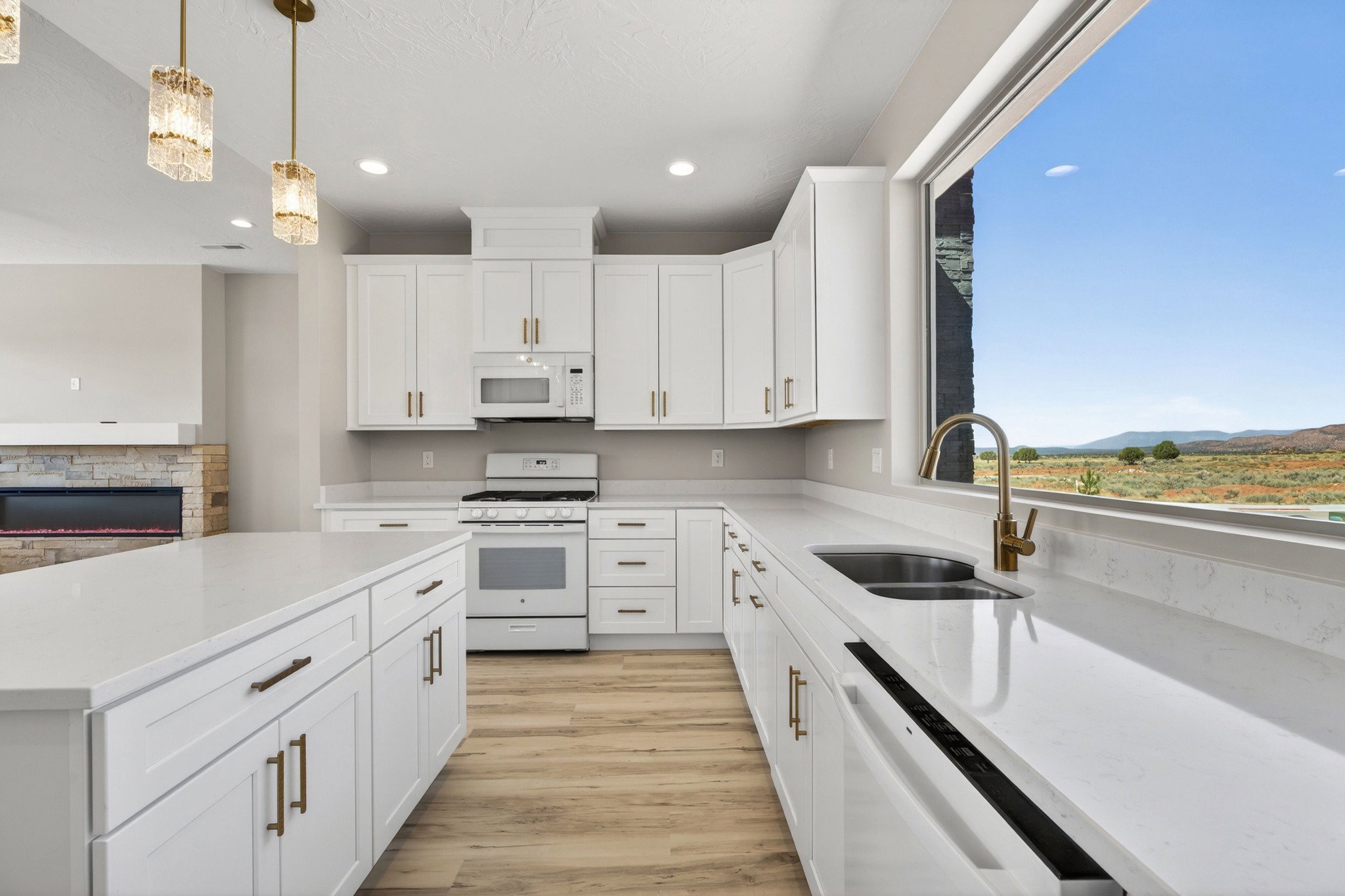 Open-concept kitchen featuring white cabinetry, light-toned countertops, and wood-finish flooring
