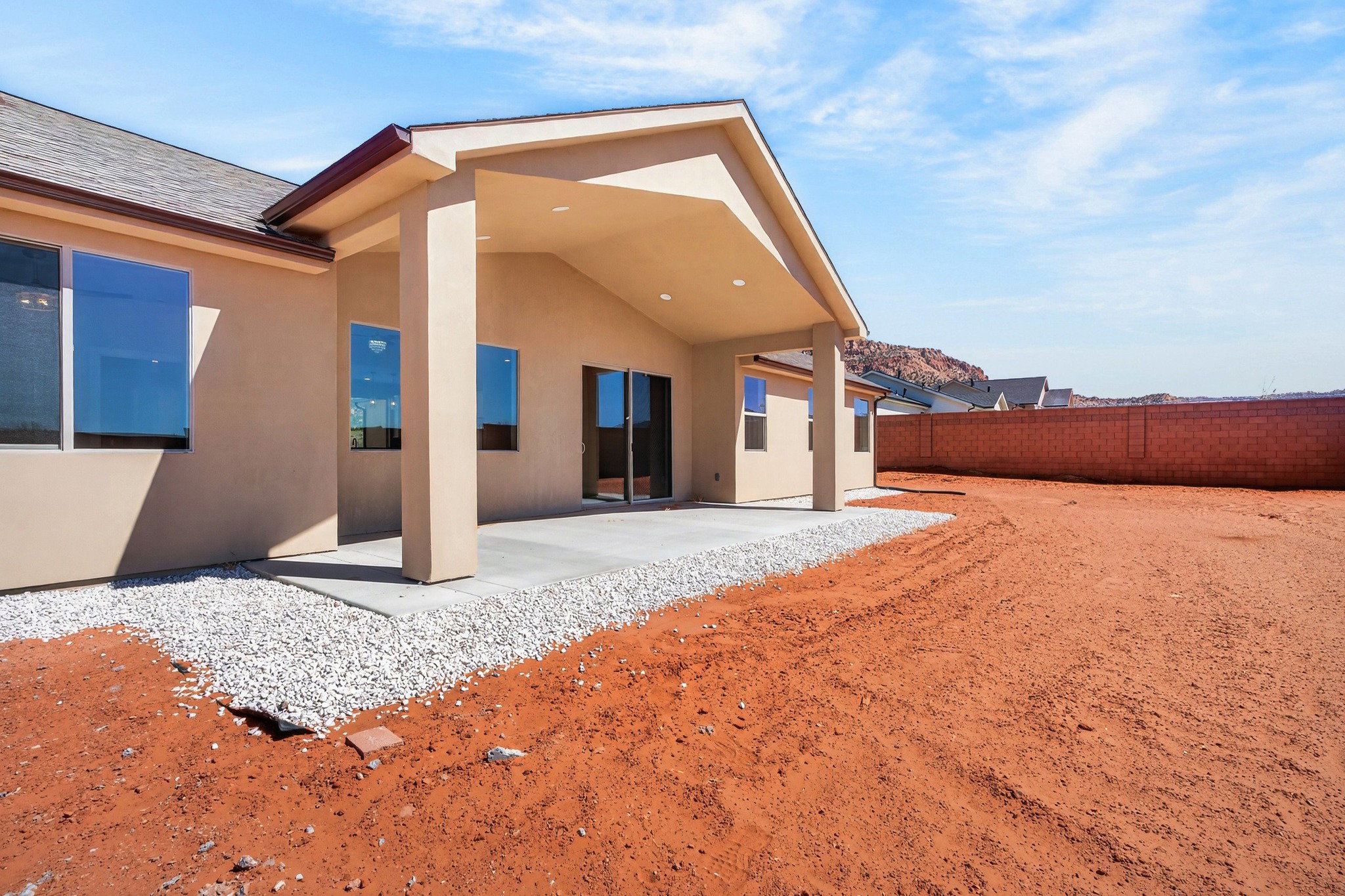 Expansive backyard with a covered patio, concrete slab, and gravel perimeter