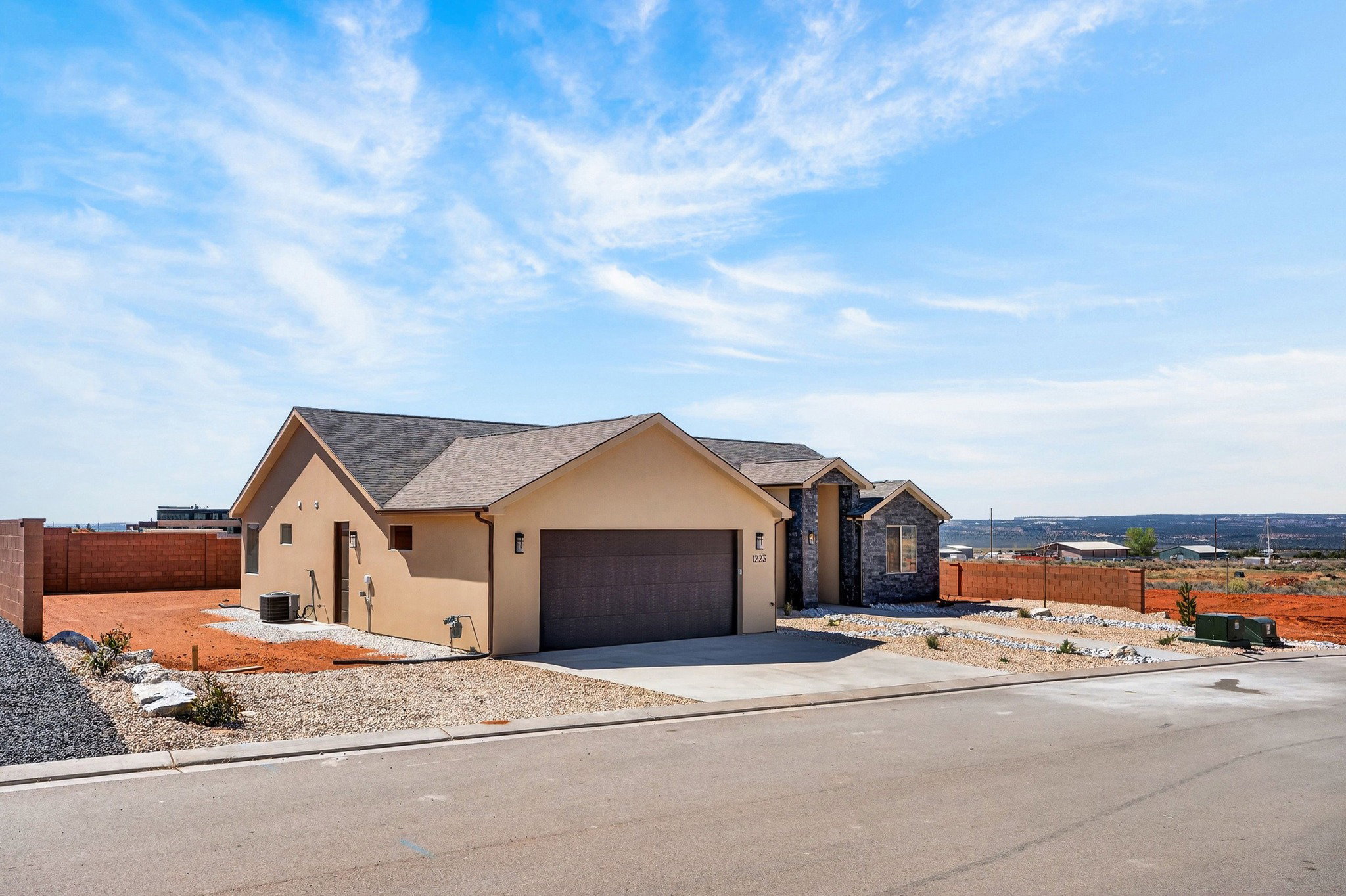 Contemporary stucco exterior with stone accents and an attached two-car garage