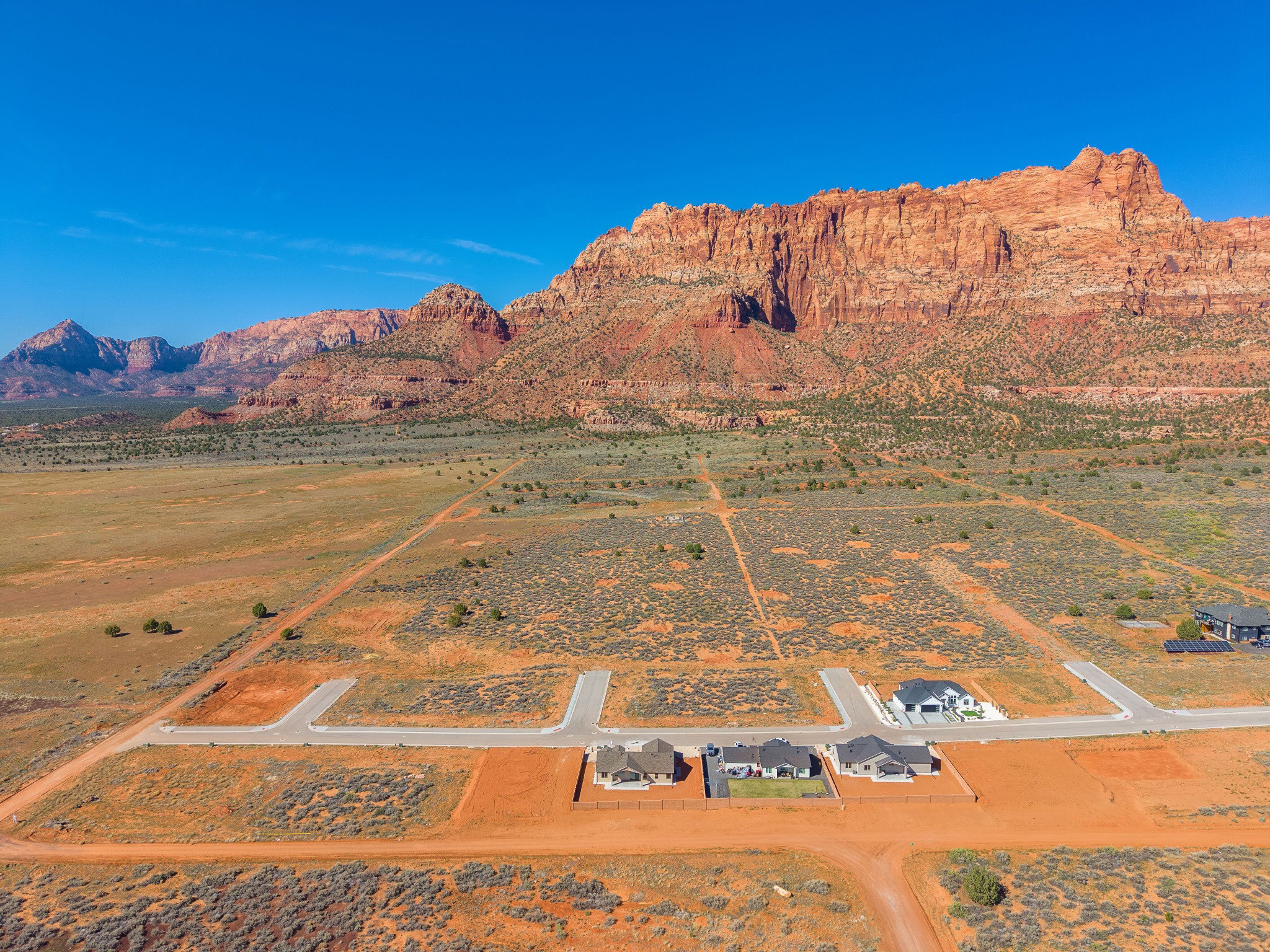 Expansive desert landscape featuring red rock mountain formations and new construction residential properties