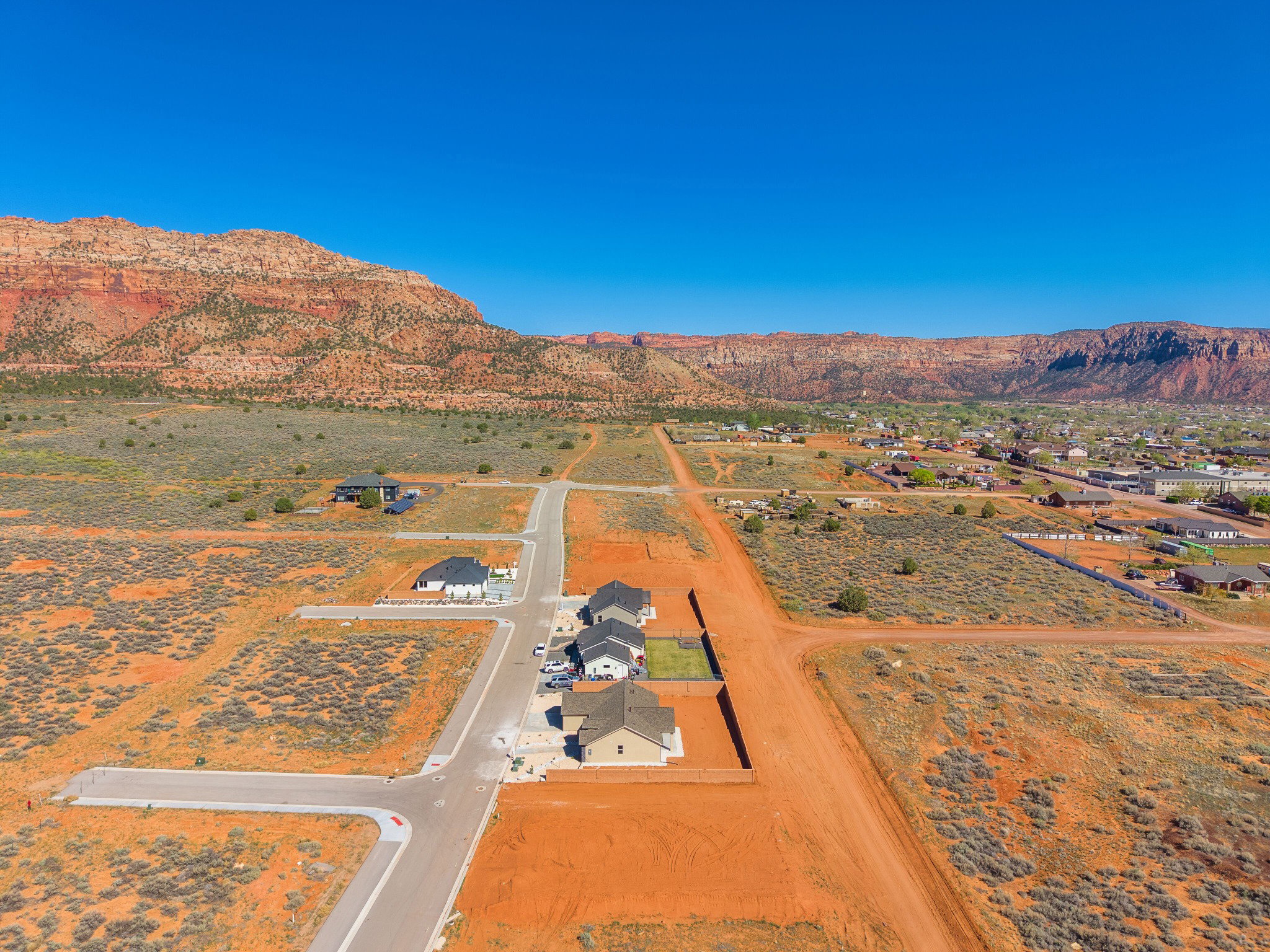 Expansive desert landscape featuring red rock mountain formations and a residential development