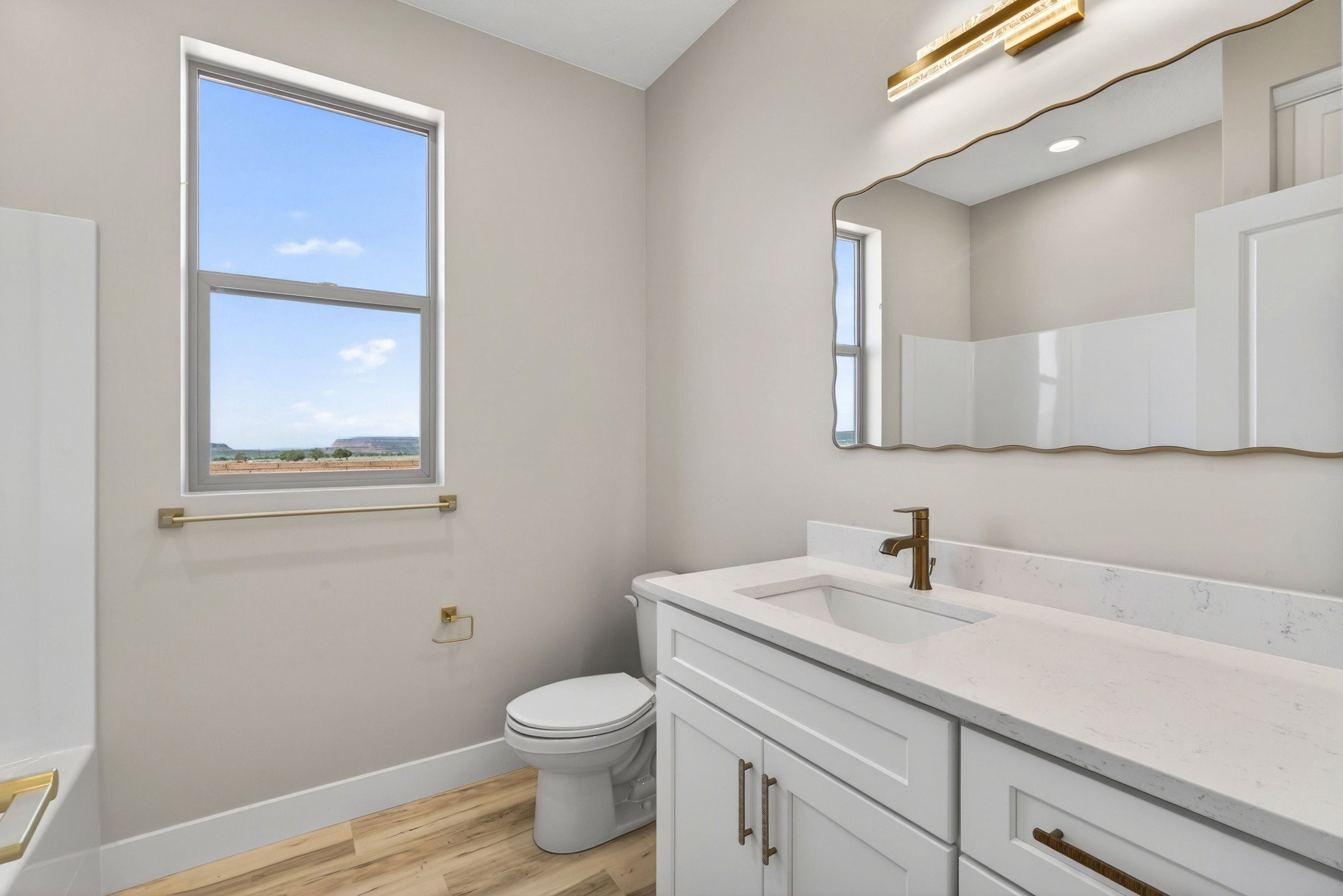 Bathroom featuring a white vanity with a light-colored countertop, an undermount sink, and a decorative mirror