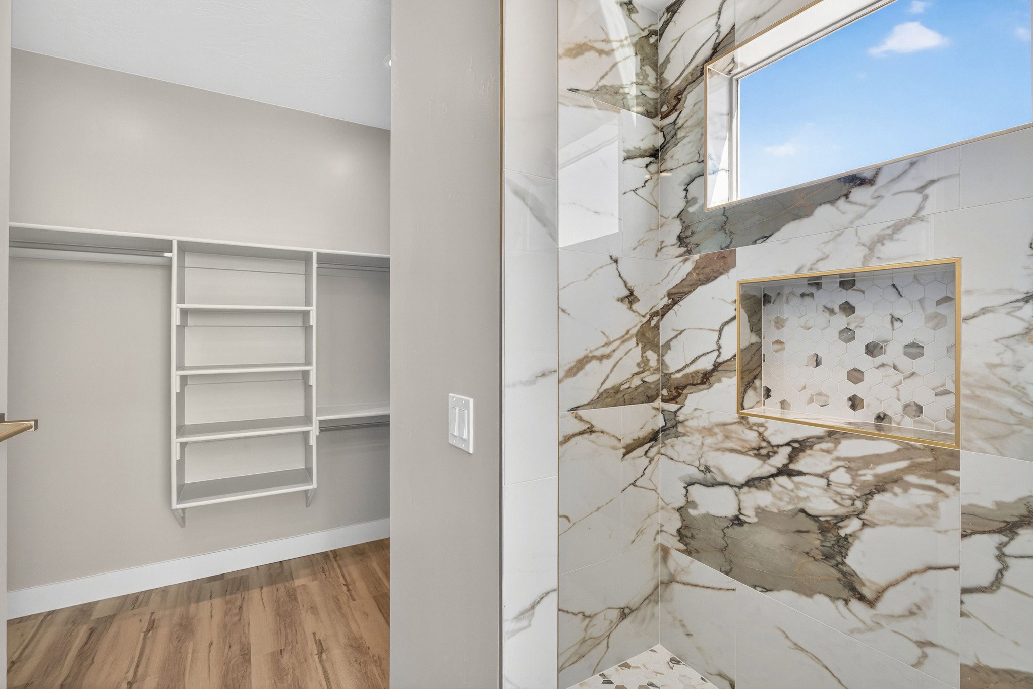 Shower with white and grey marble-look tile, a rectangular window, and a built-in niche with hexagonal tile inlay