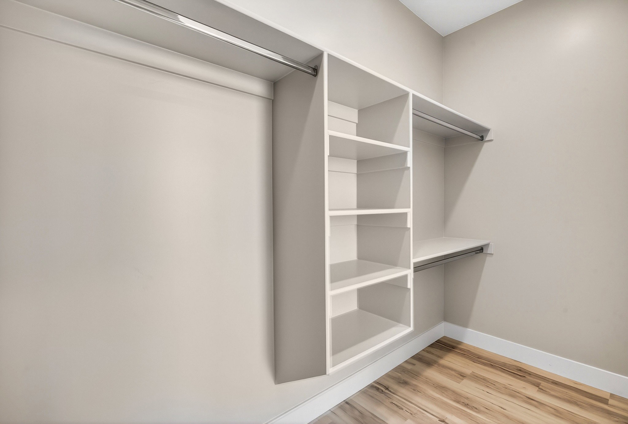 Walk-in closet featuring built-in shelving, multiple hanging rods, and wood-finish flooring