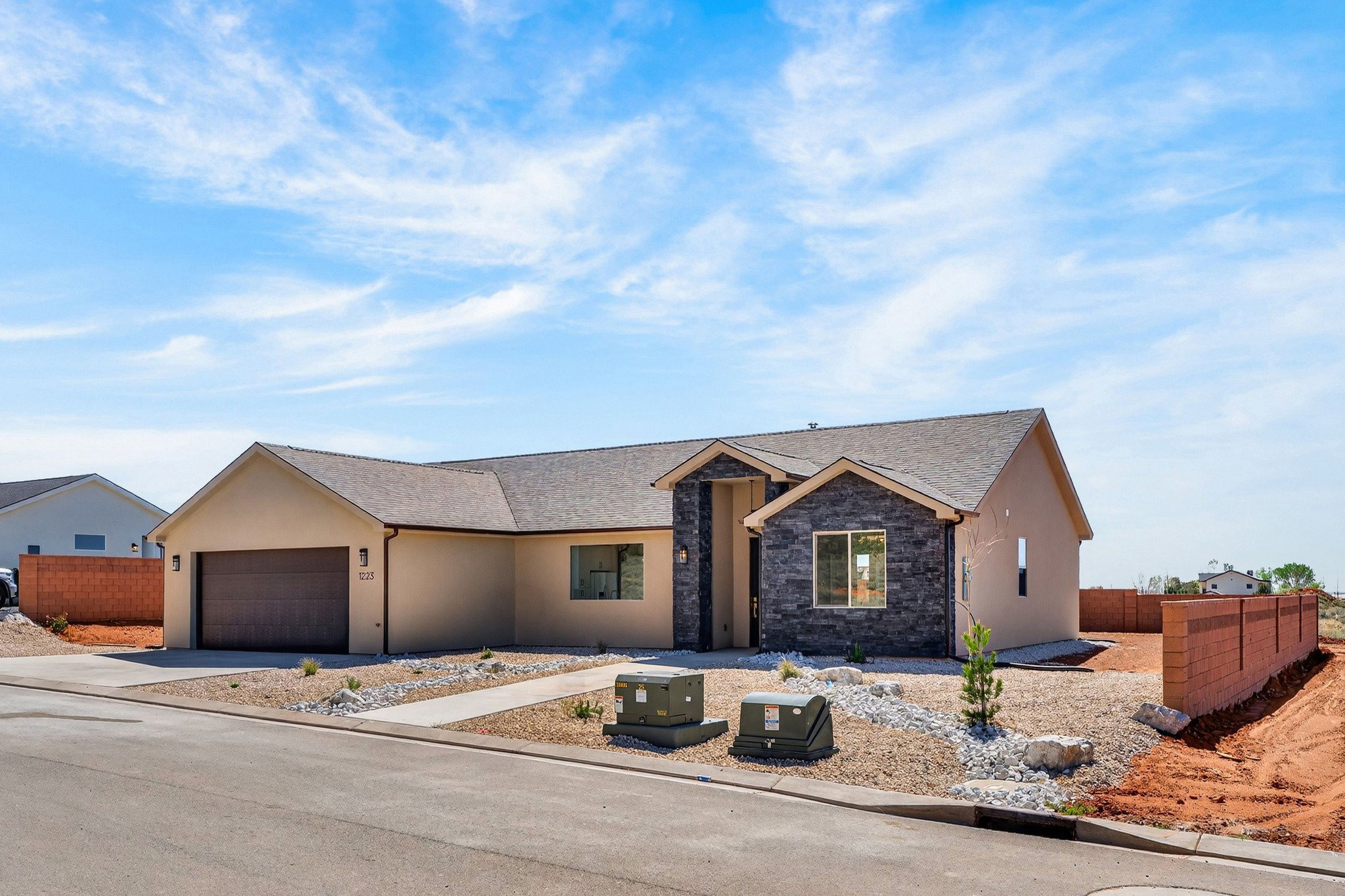 Contemporary ranch-style residence featuring a stucco exterior with stone facade accents