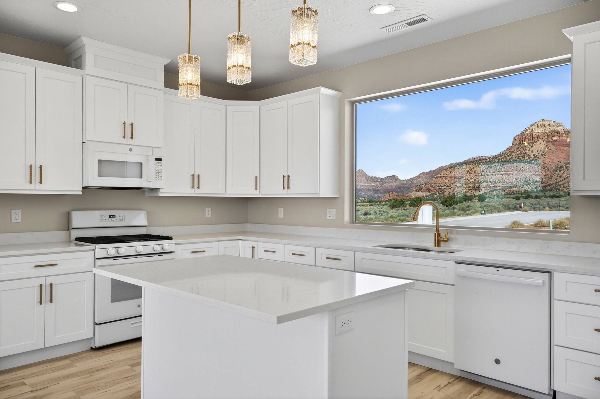 Bright kitchen featuring white cabinetry, a large picture window, a central island with a solid surface countertop, wood-finish flooring, and pendant lighting fixtures