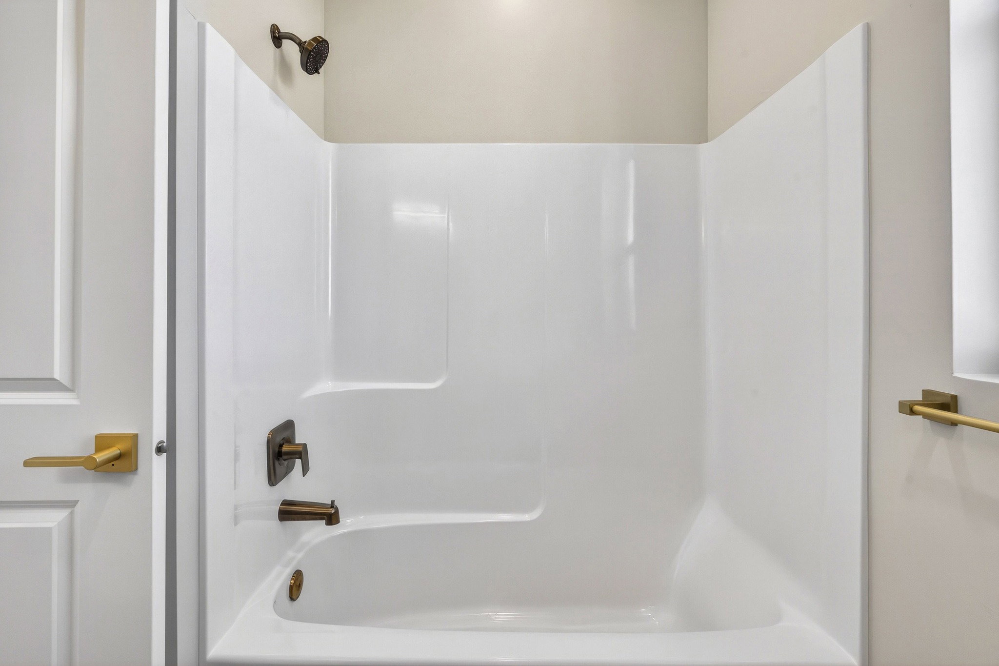 White acrylic tub and shower combination with bronze fixtures