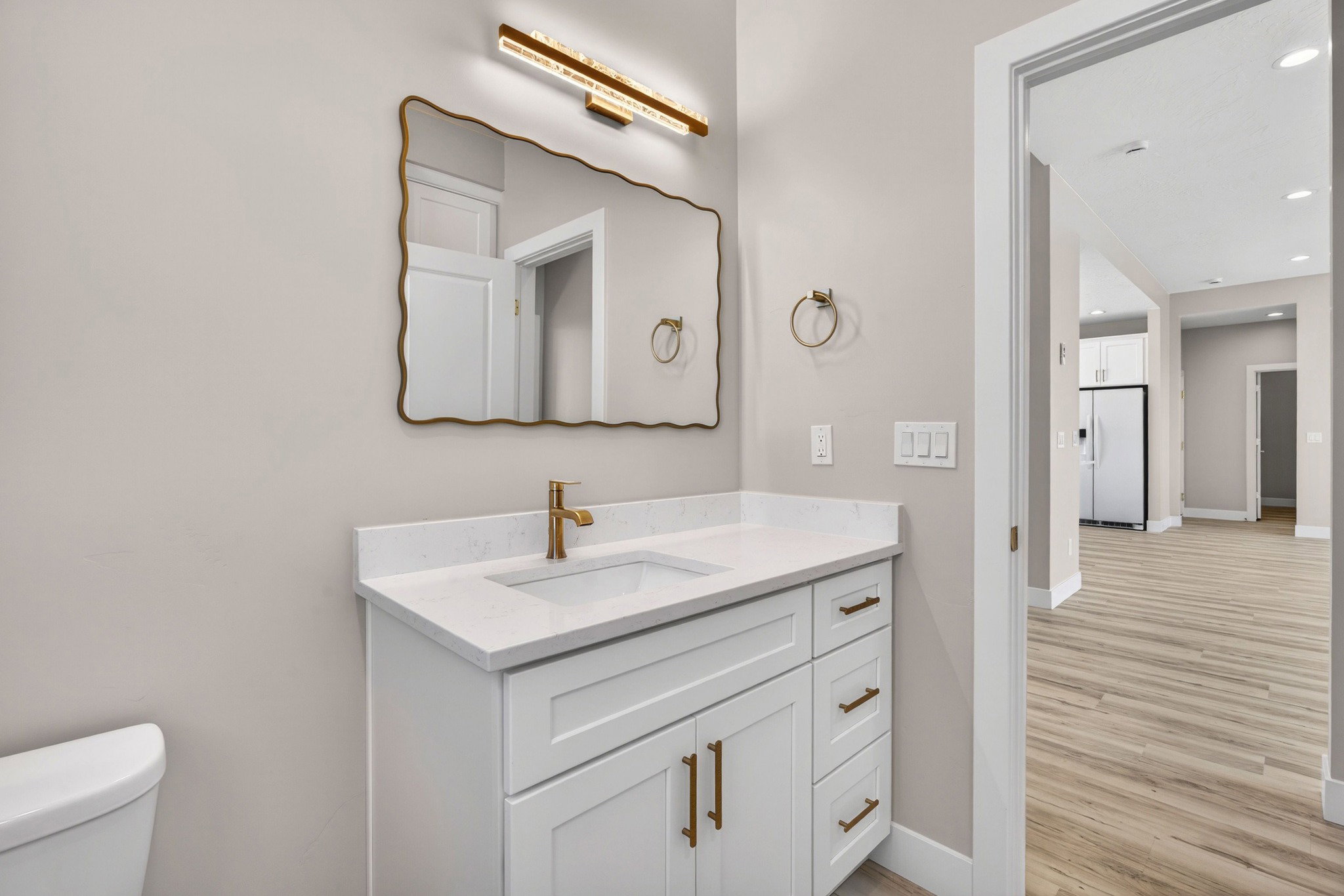Bathroom vanity featuring a white cabinet, integrated sink, gold-tone faucet, and gold-tone hardware