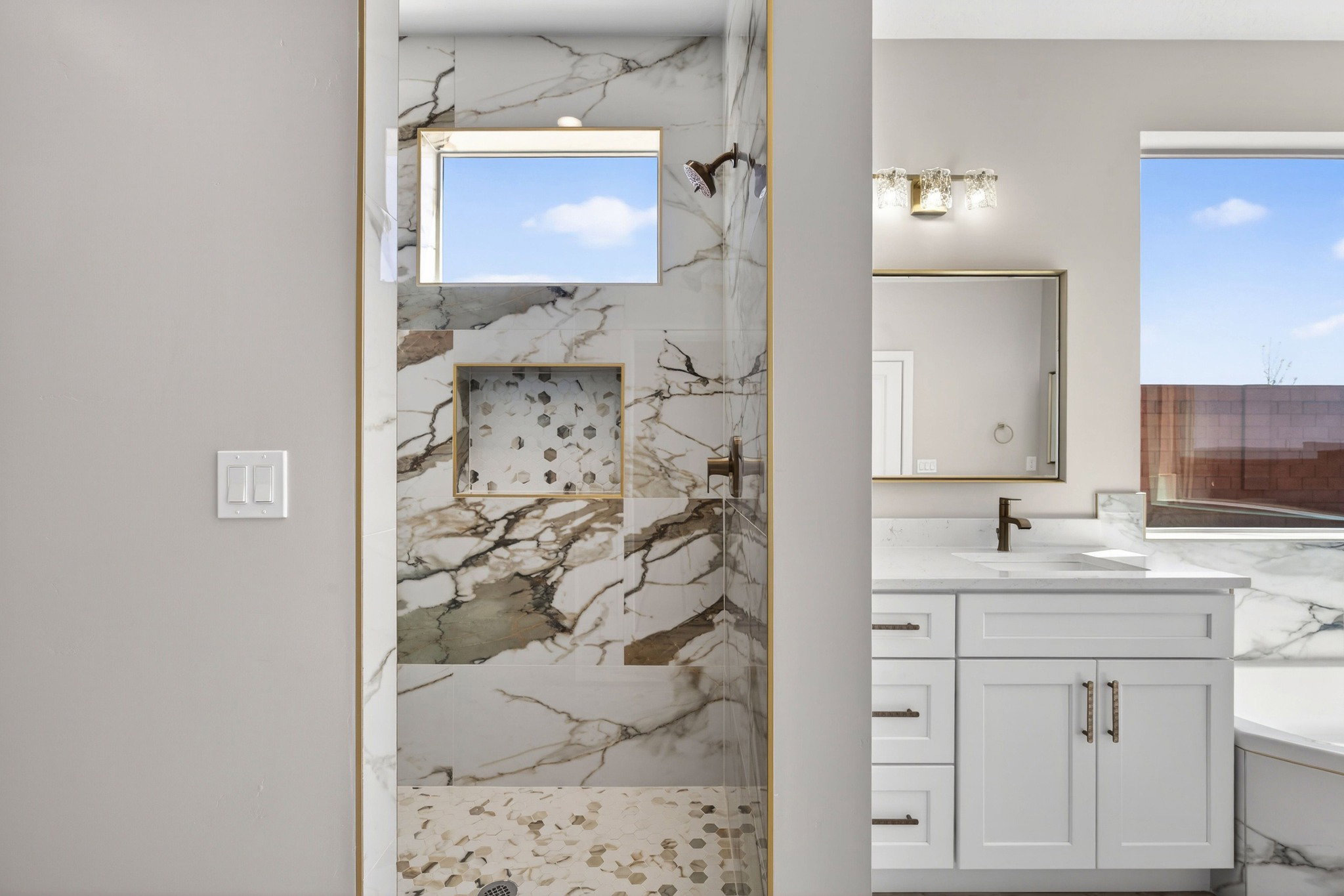 Contemporary bathroom featuring a walk-in shower with marble-look wall tile, a mosaic tile floor, and an integrated niche