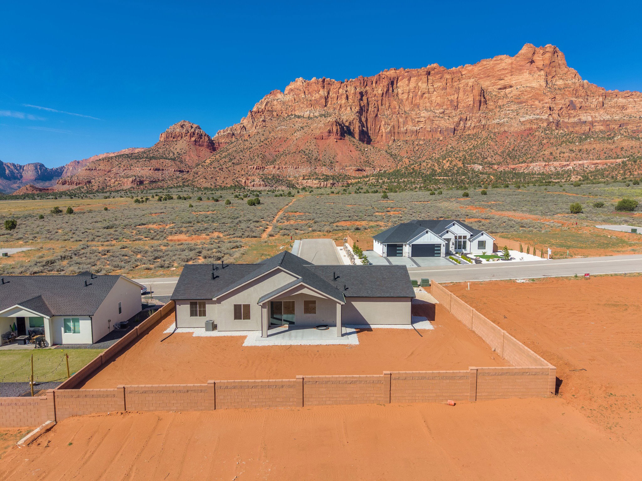 New construction residence featuring a stucco exterior, dark shingle roof, and an expansive paved patio