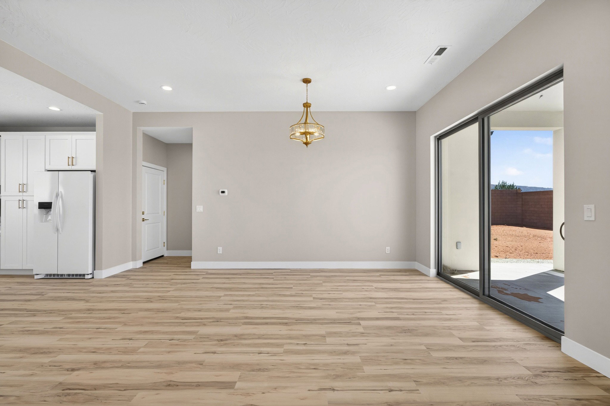 Expansive interior space featuring wood-finish flooring and a contemporary brass chandelier