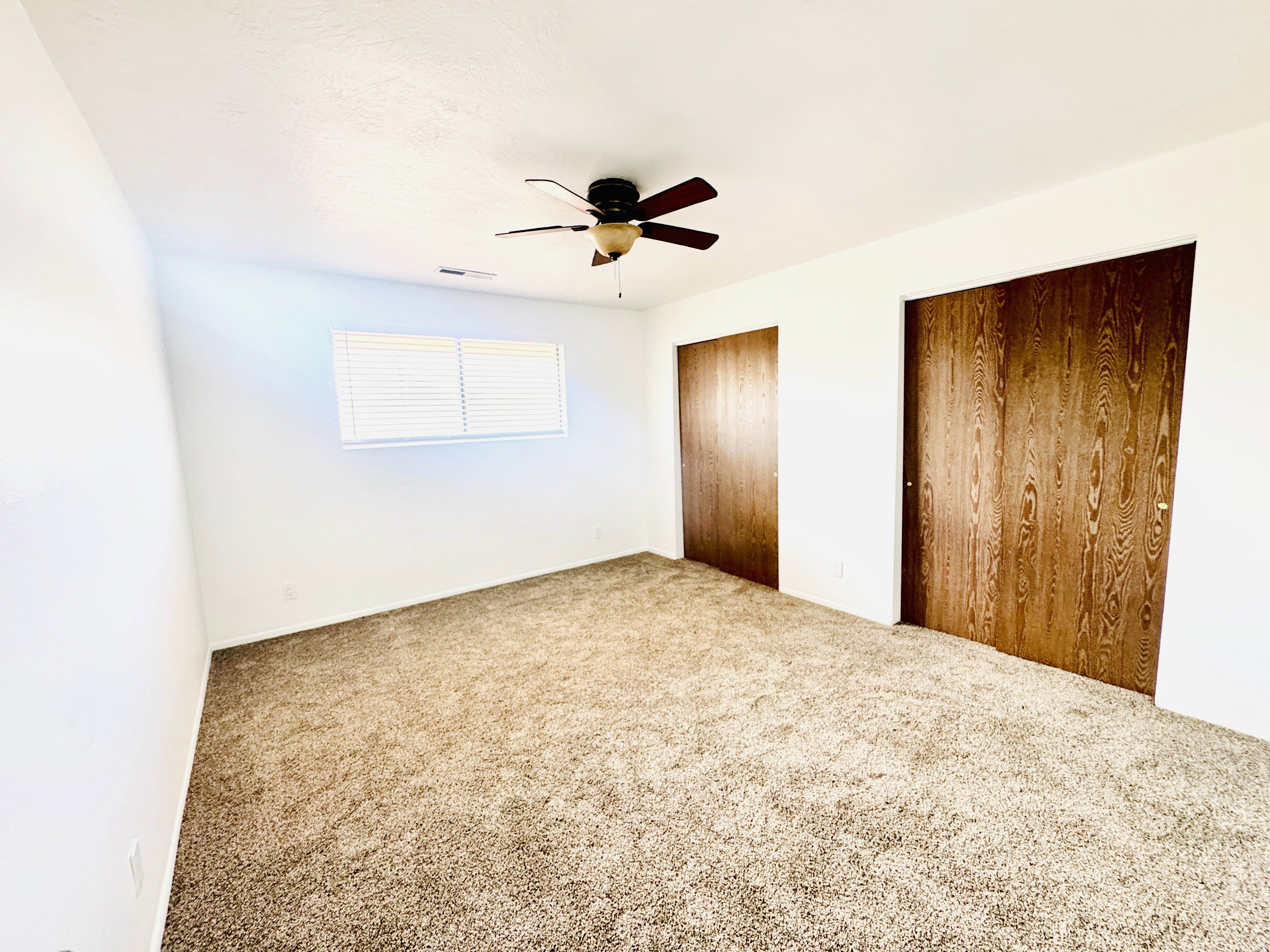 Room featuring neutral-toned carpet flooring, white walls, and a ceiling fan with light fixture