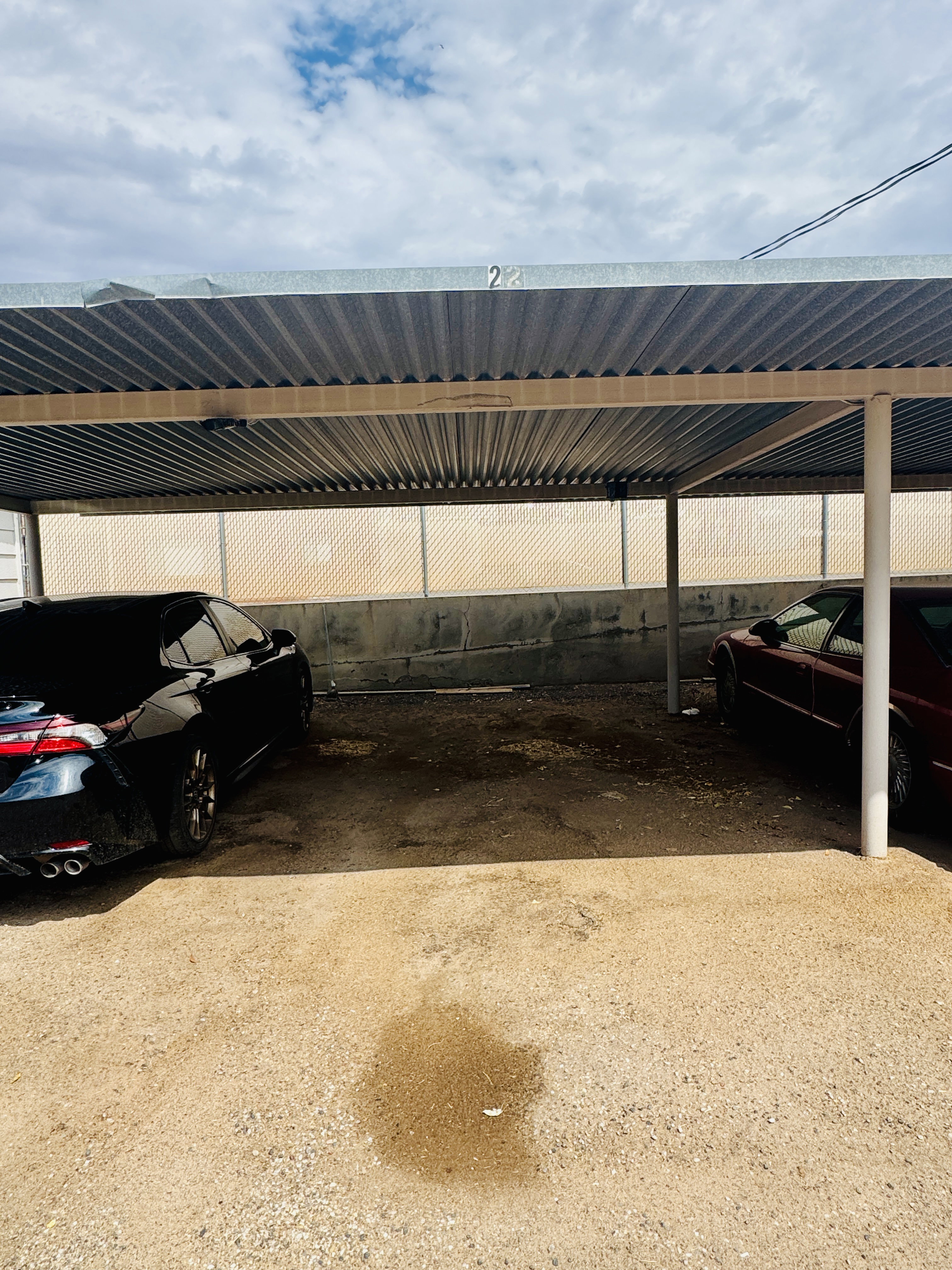 Covered parking structure with a corrugated metal roof and white support columns