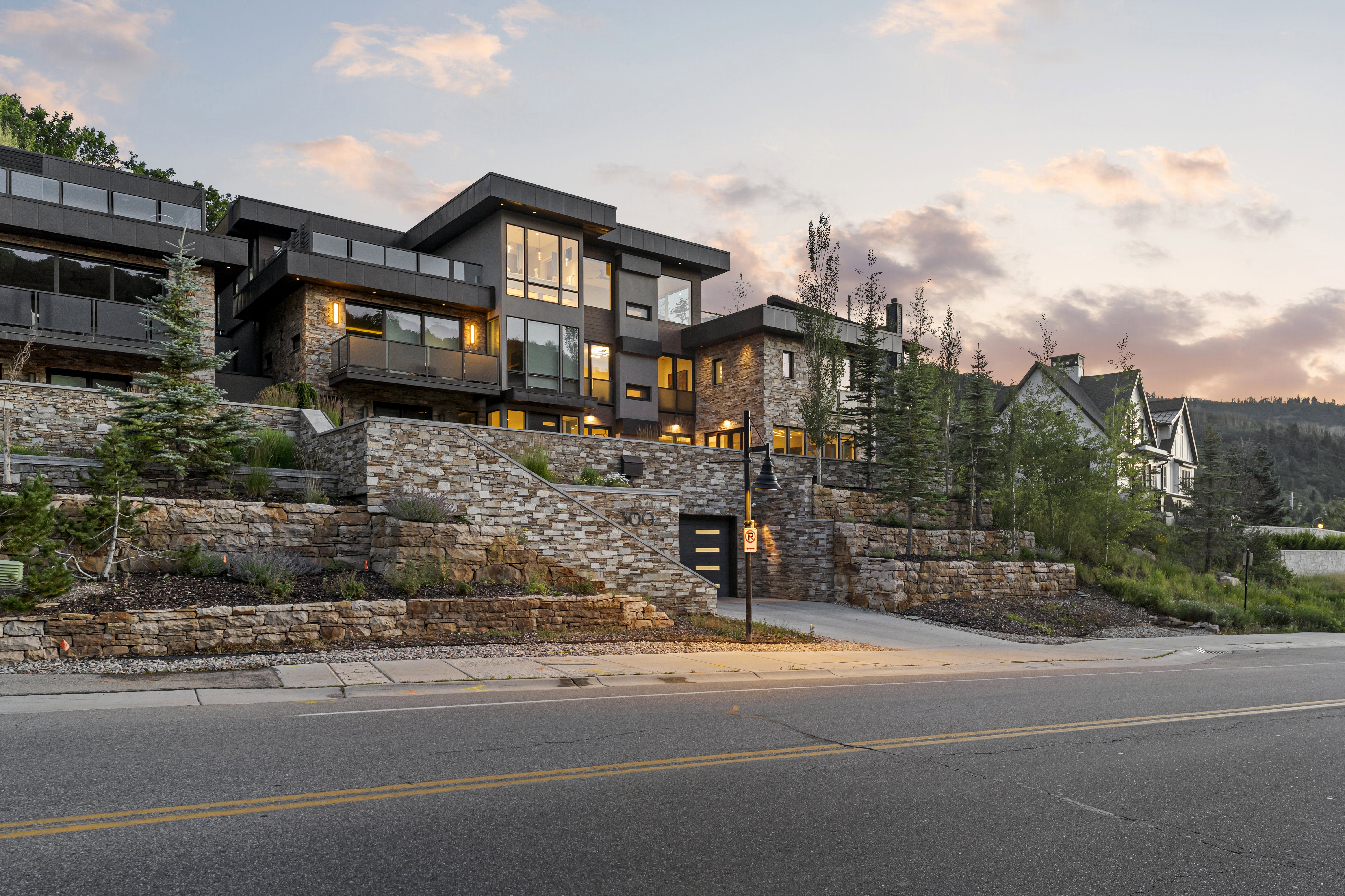 Contemporary multi-level residence featuring expansive windows, private balconies with glass railings, and a stone facade