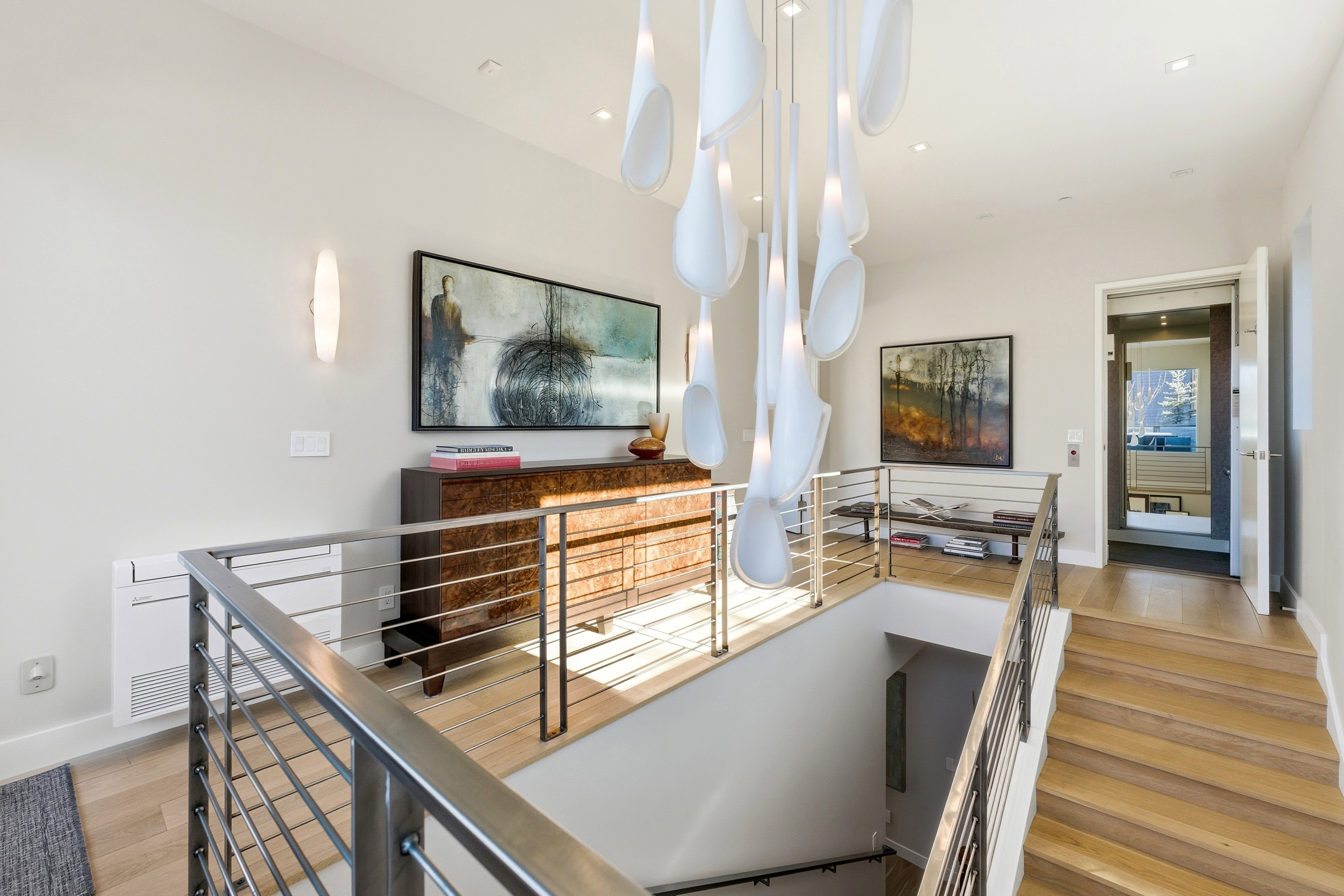 Upper landing featuring a contemporary chandelier, hardwood flooring, and stainless steel cable railings