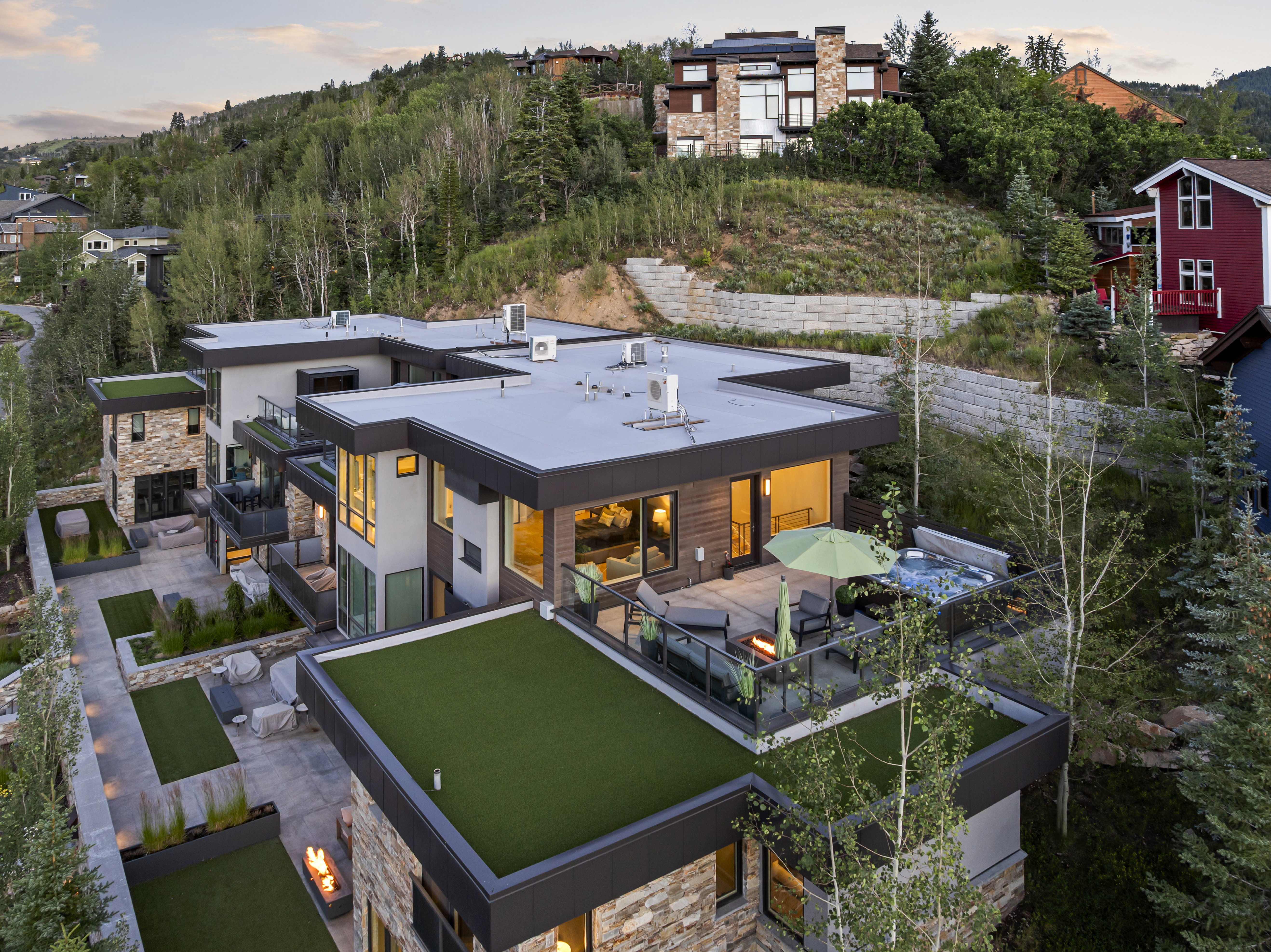 Modern multi-level residence featuring flat roofs, stone cladding, and extensive glass windows