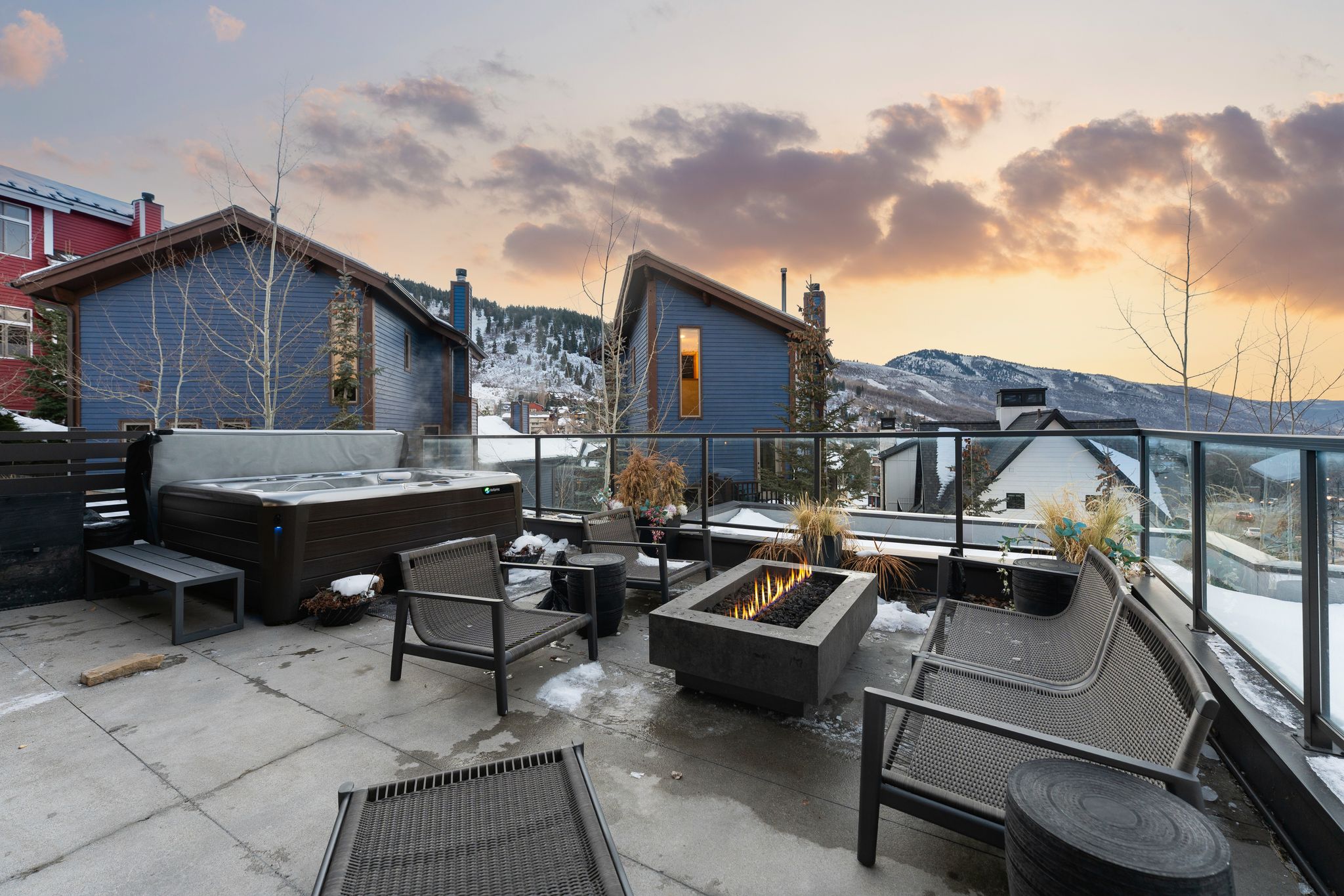 Expansive outdoor patio featuring a hot tub, a built-in fire pit, and a glass-paneled railing