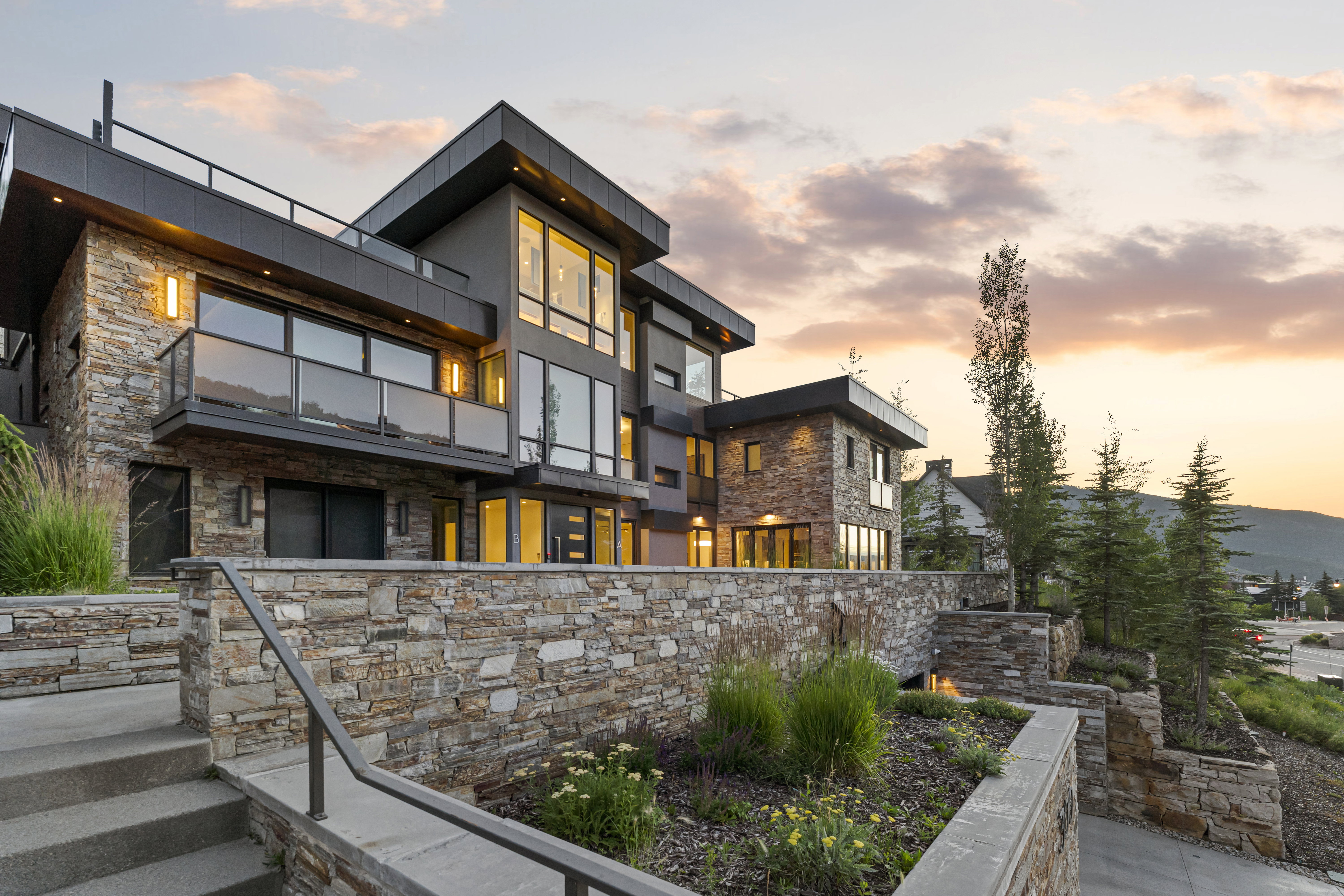 Modern architectural exterior featuring stone veneer and dark-toned siding