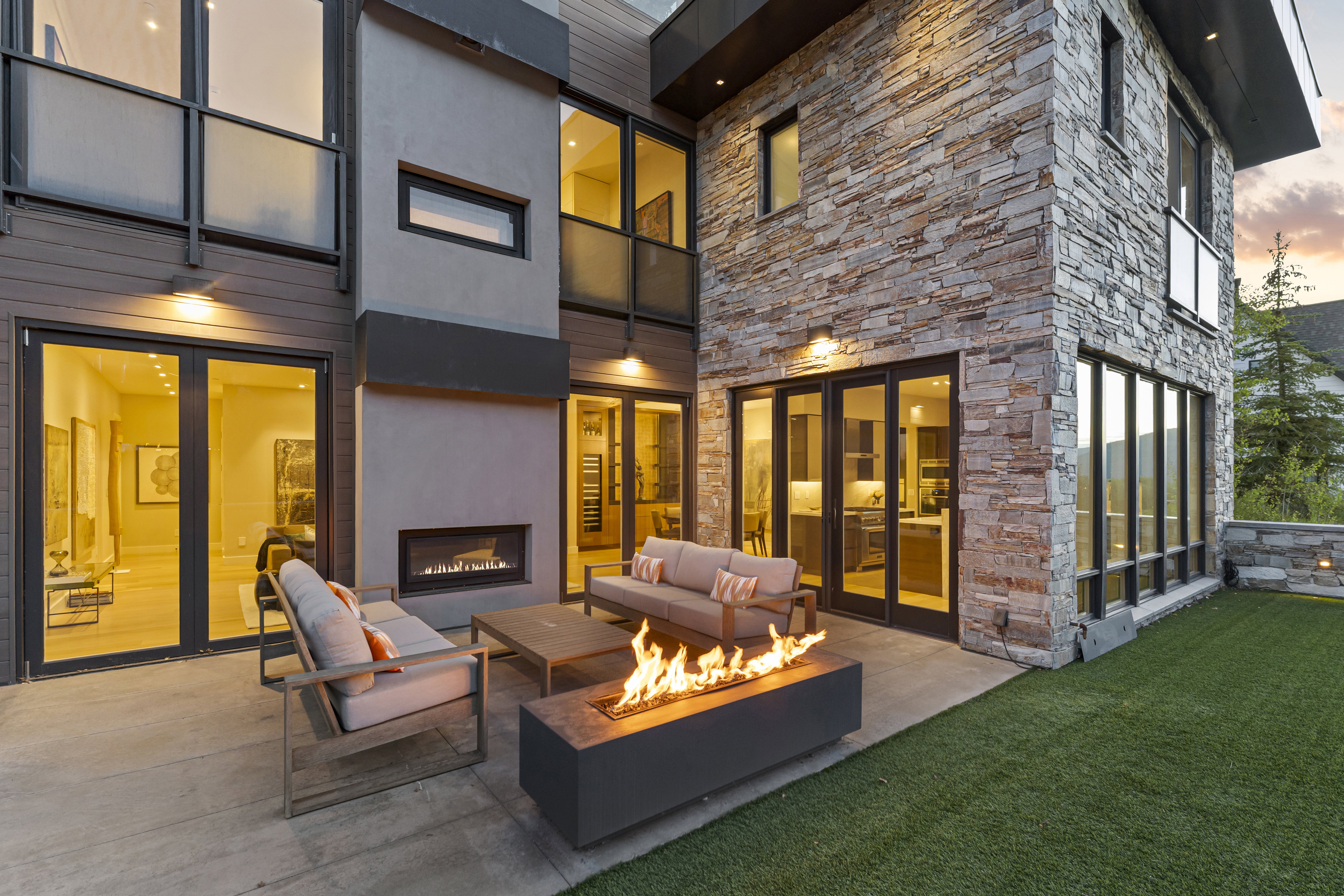 Expansive outdoor patio featuring a built-in fireplace, concrete flooring, and surrounding artificial turf