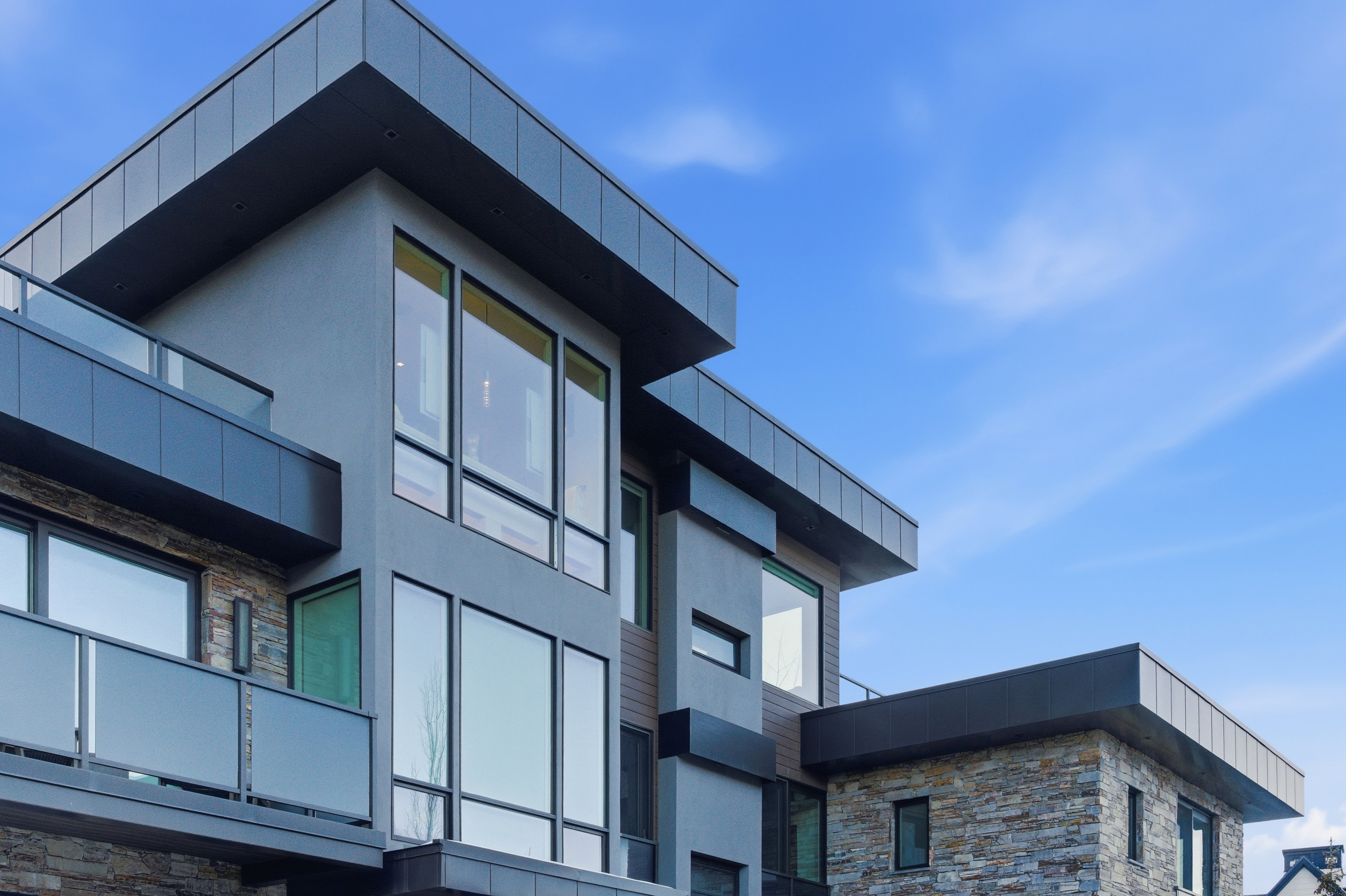 Contemporary multi-level exterior featuring stucco, stacked stone, and vertical wood-finish siding