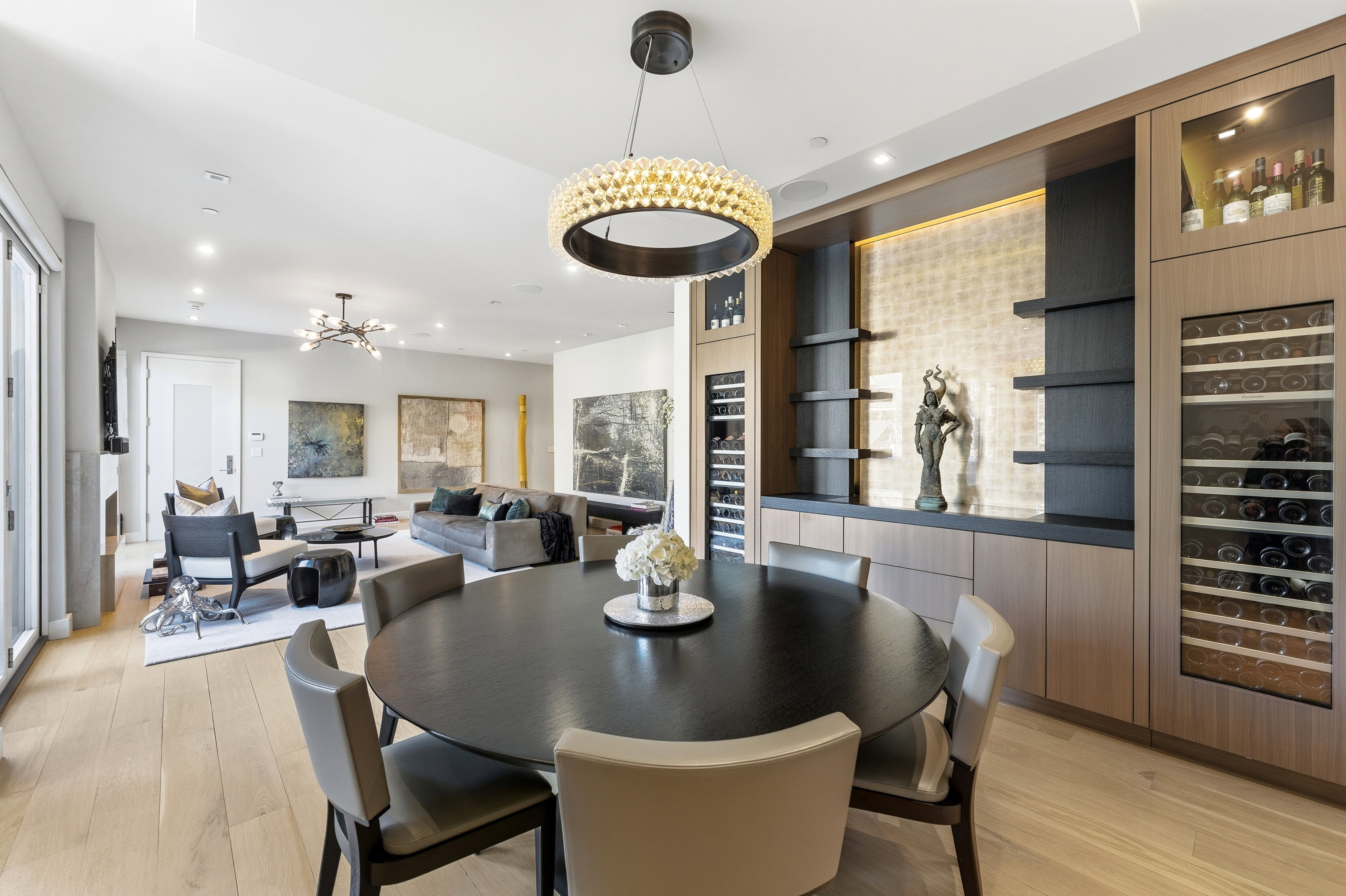 Open-concept living space featuring wood-finish flooring, a built-in beverage storage wall, recessed lighting, and a modern chandelier