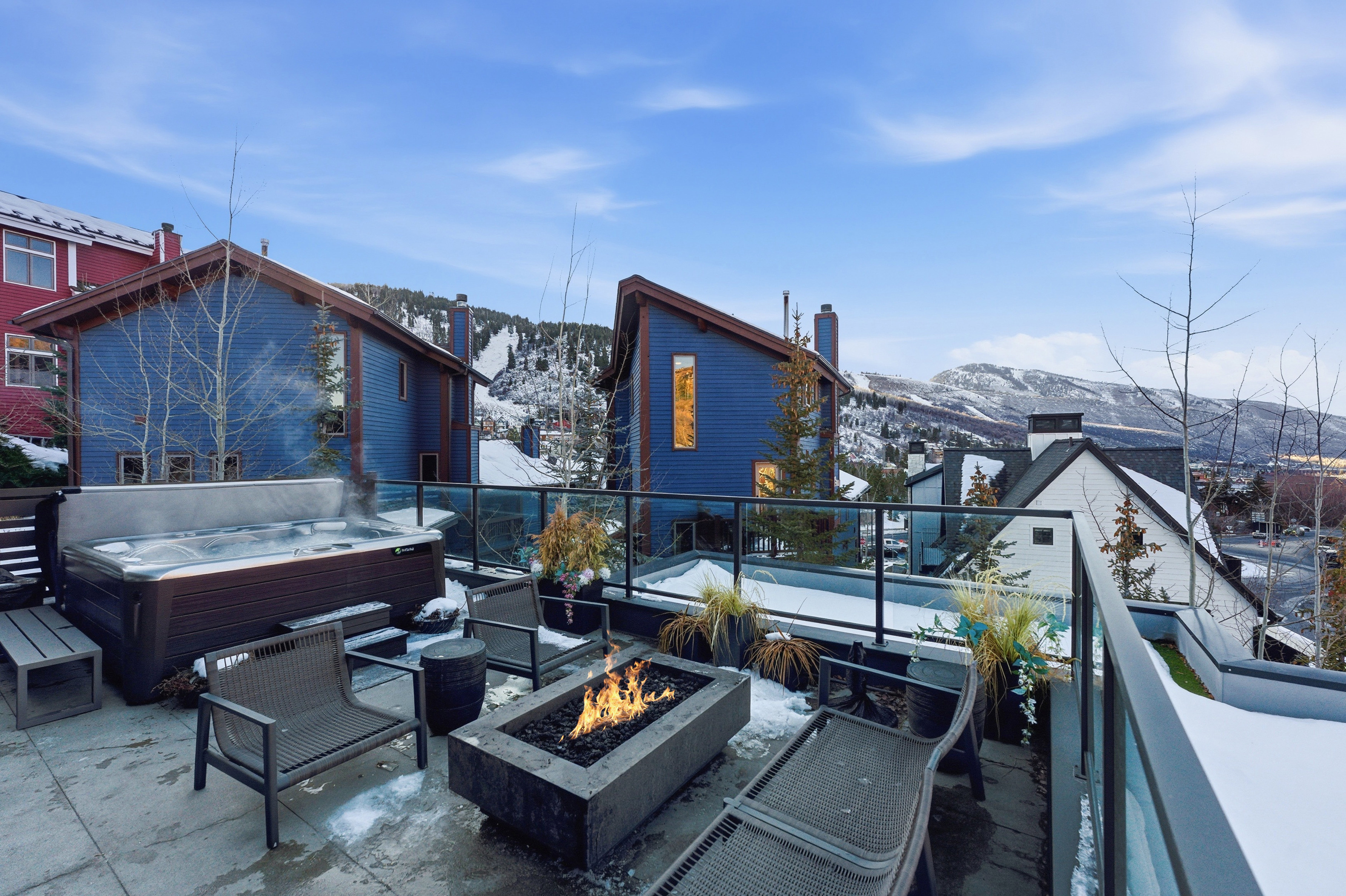 Rooftop terrace featuring a built-in hot tub, concrete fire pit, and glass railing system