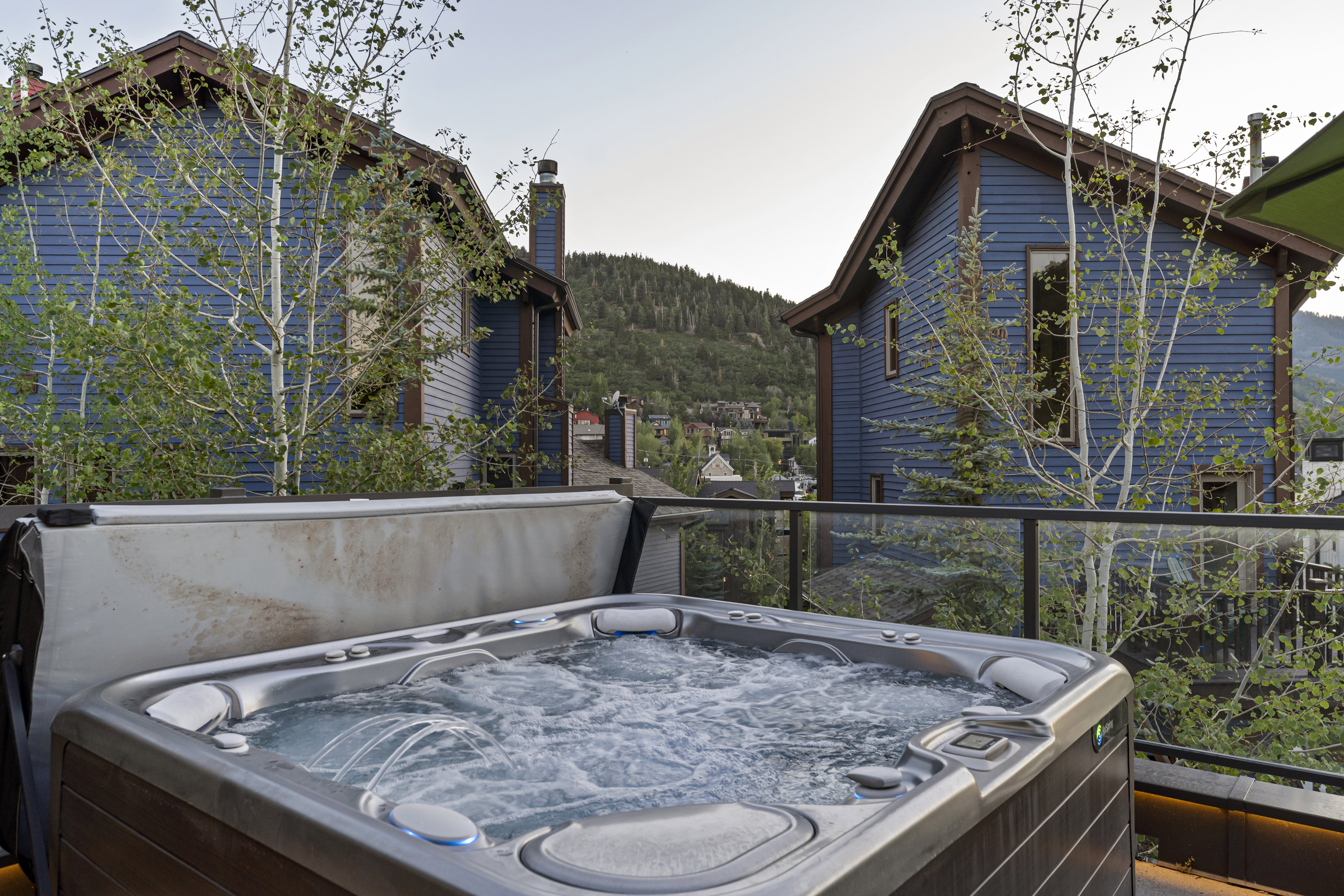 Outdoor hot tub with bubbling water on a balcony featuring a glass railing