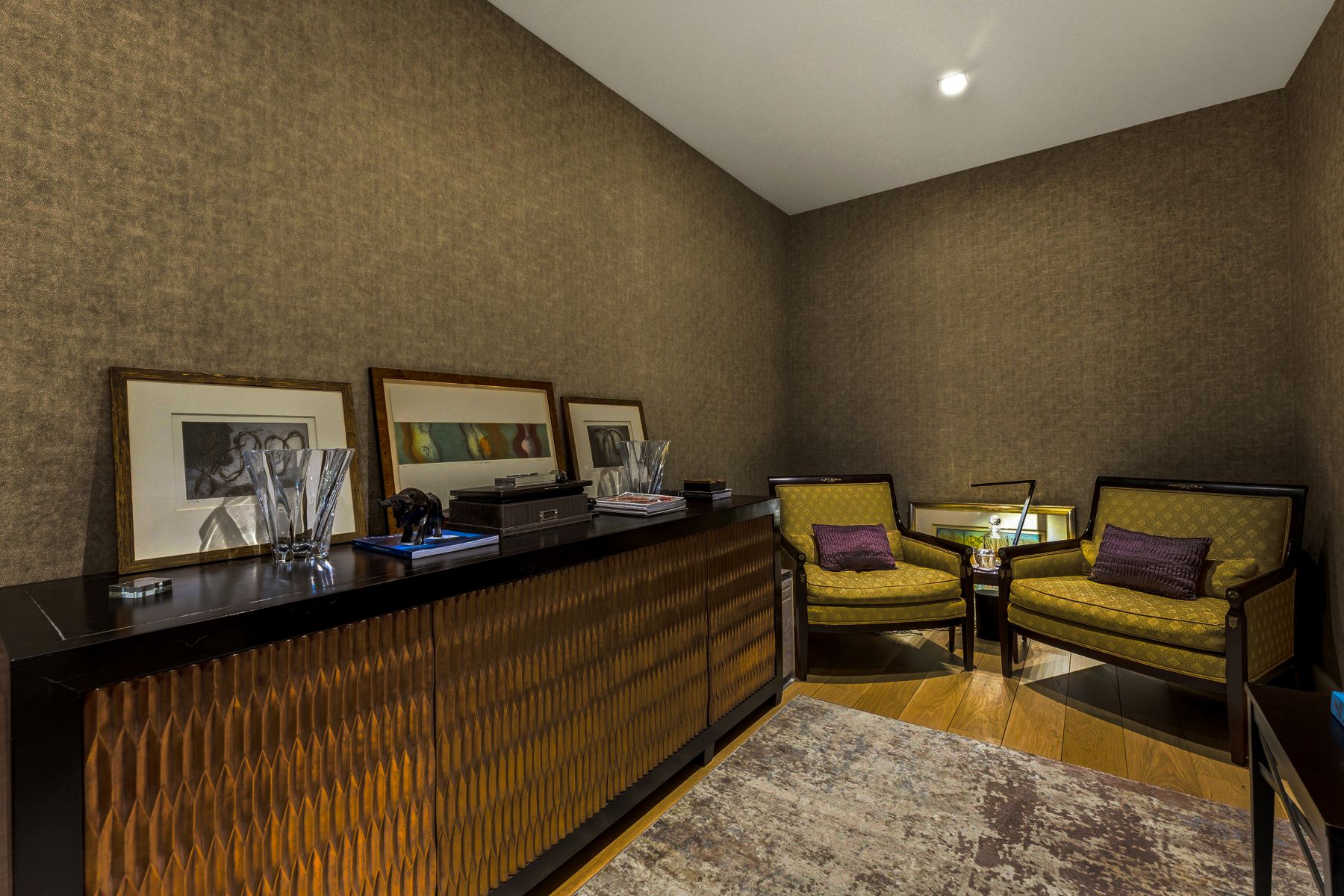 Textured wall covering in a warm tone, featuring a built-in credenza with a textured wood-finish facade and a dark countertop